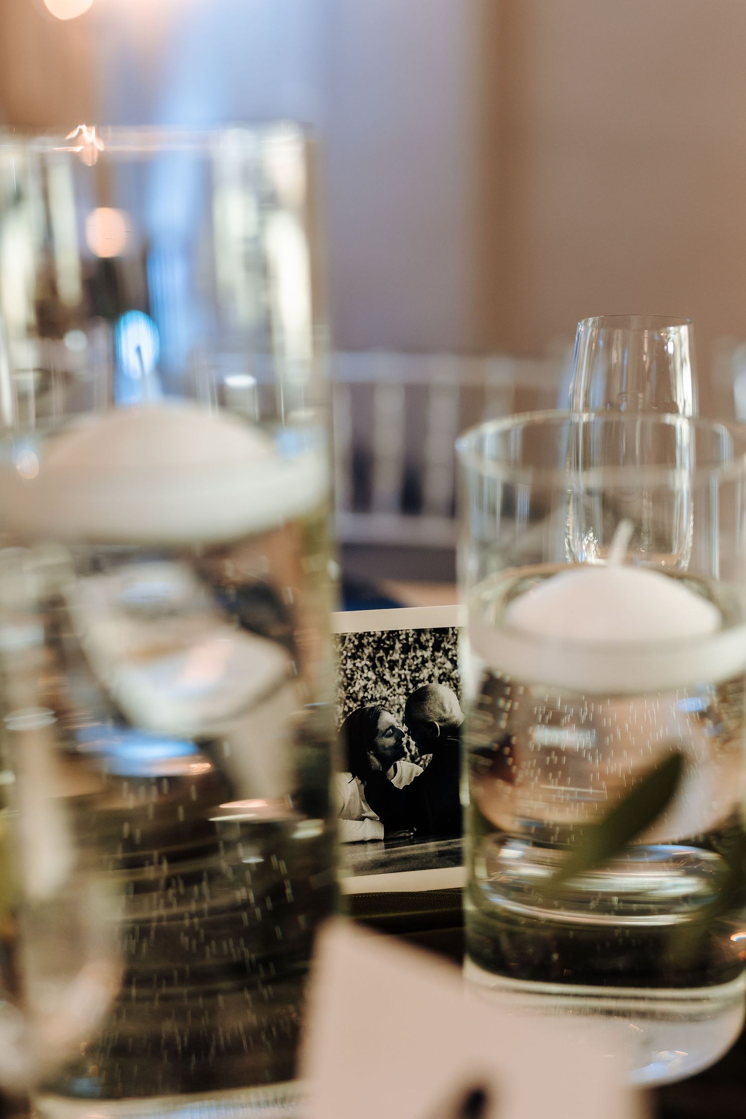 Artistic wedding table decor with floating candles in glass vessels and decorative cards.