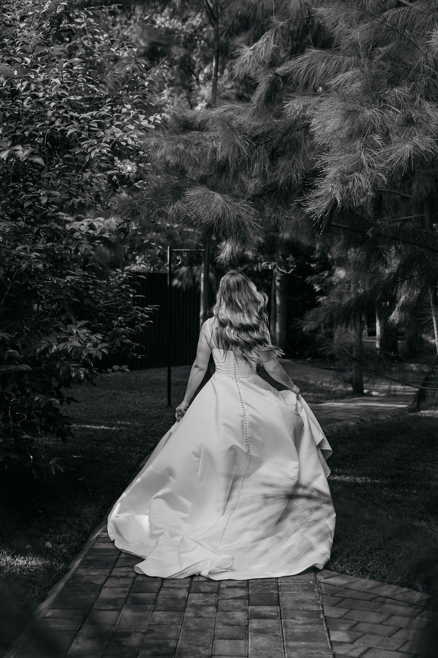 A black and white photo series showing a flowing white dress moving in the wind against a dark garden background.
