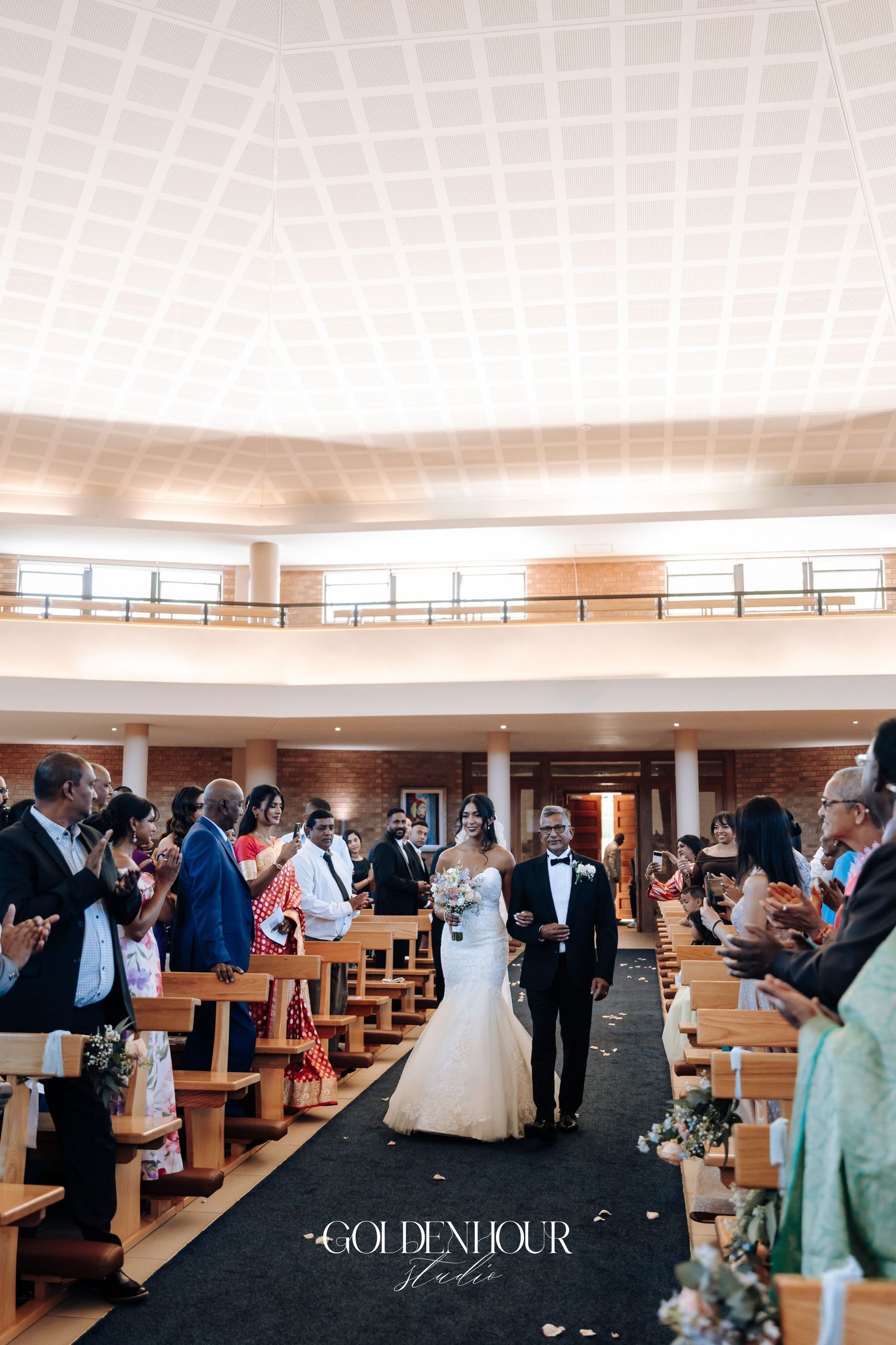 Wedding ceremony in modern church with guests seated in wooden pews.