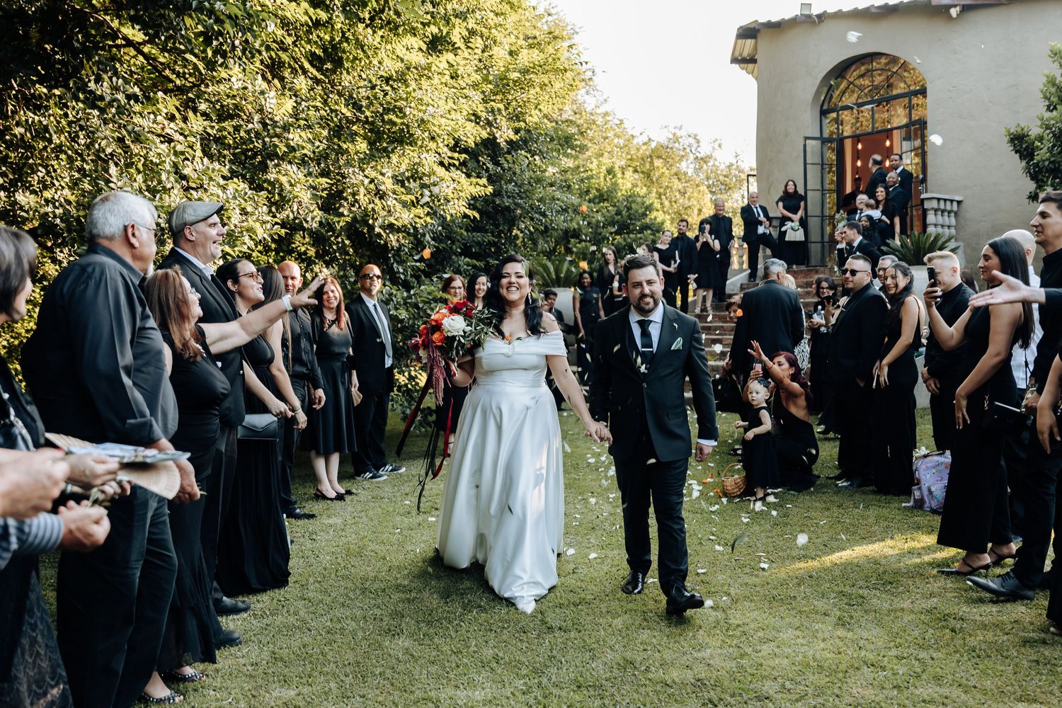 Wedding guests gathered outdoors on a sunny day for group photos.