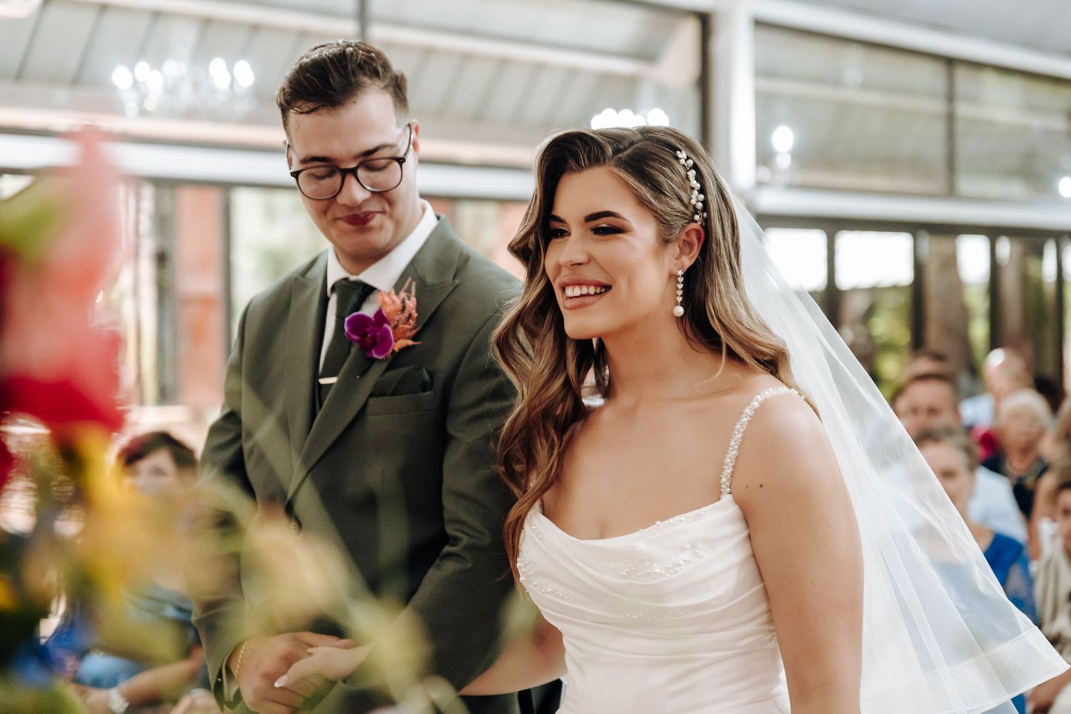 Wedding celebration in a light-filled venue with elegant decor and chandeliers overhead.
