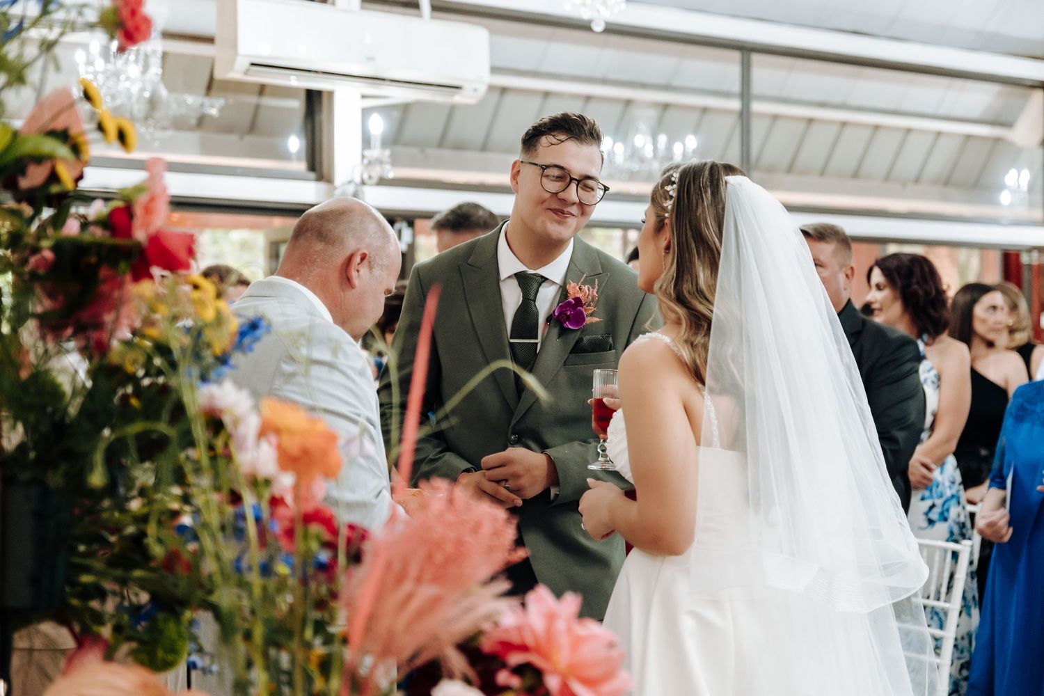 Joyful wedding moment captured as guests shower the couple with pink confetti in a light-filled venue.