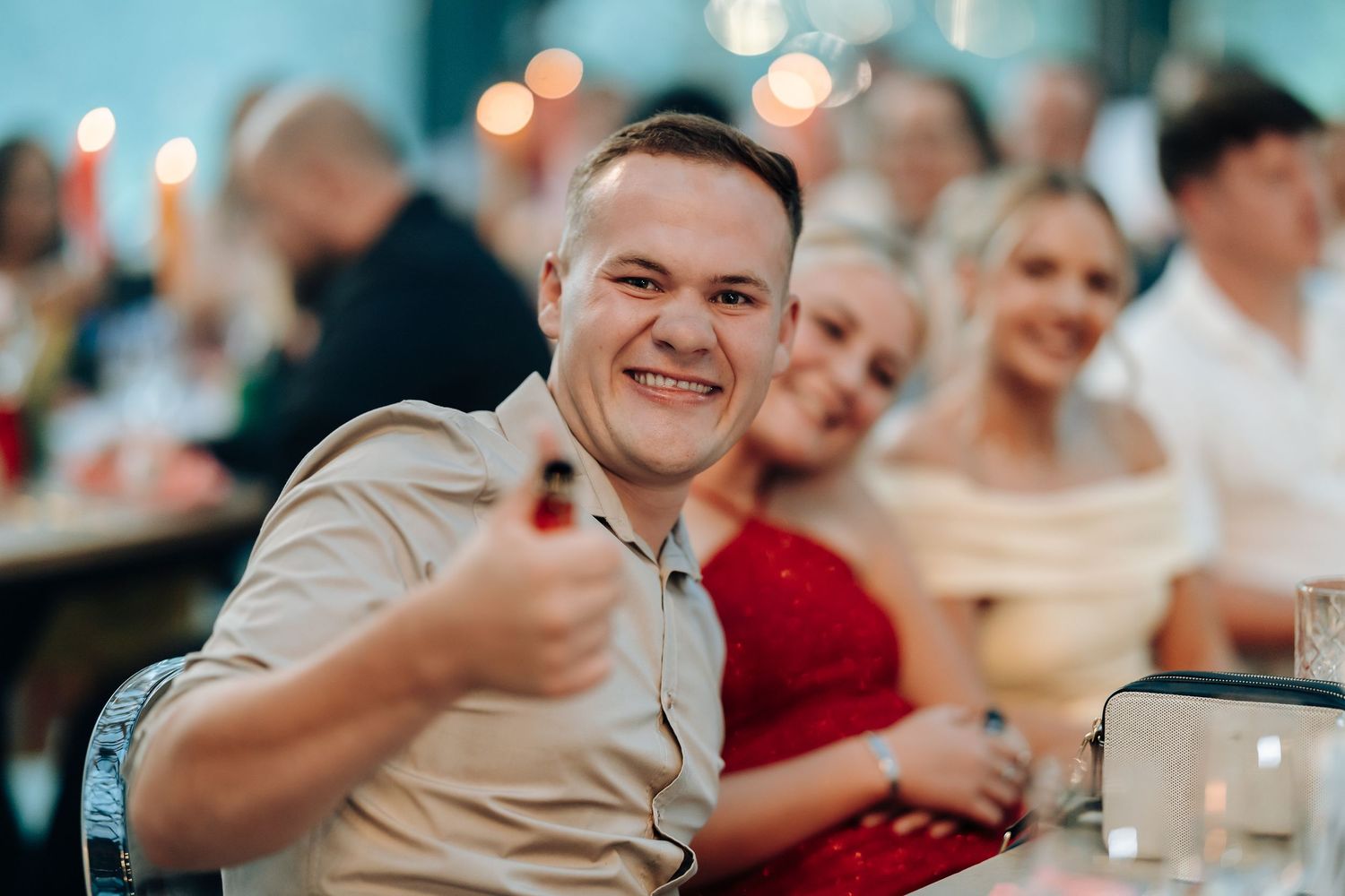Wedding guests laughing and enjoying themselves at an indoor reception with warm lighting and festive atmosphere.