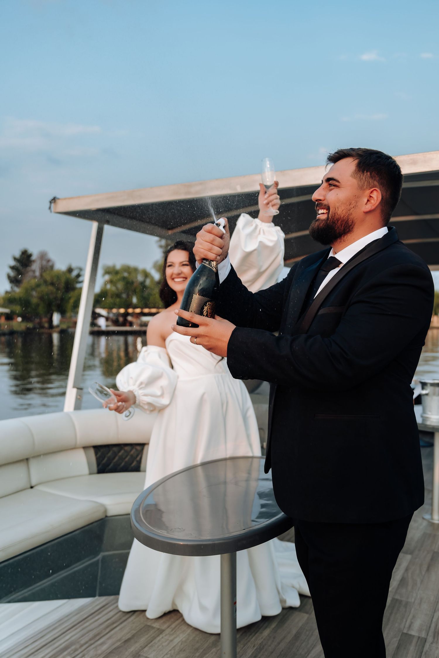 Wedding party members taking celebratory shots together on a boat deck during sunset festivities.