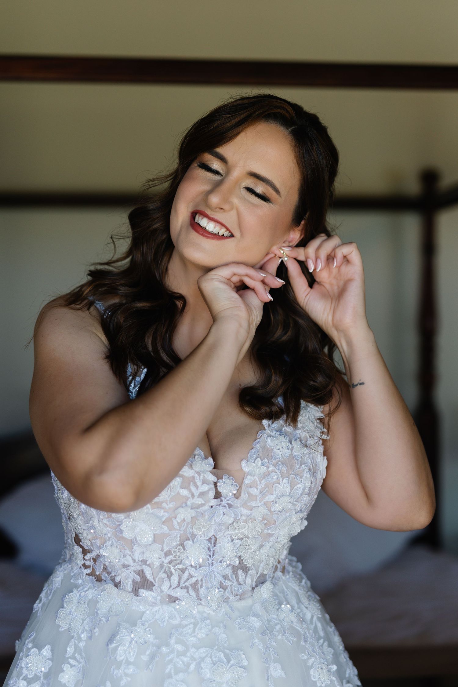 A joyful bride in a white lace wedding dress laughs candidly during a pre-wedding photo session.