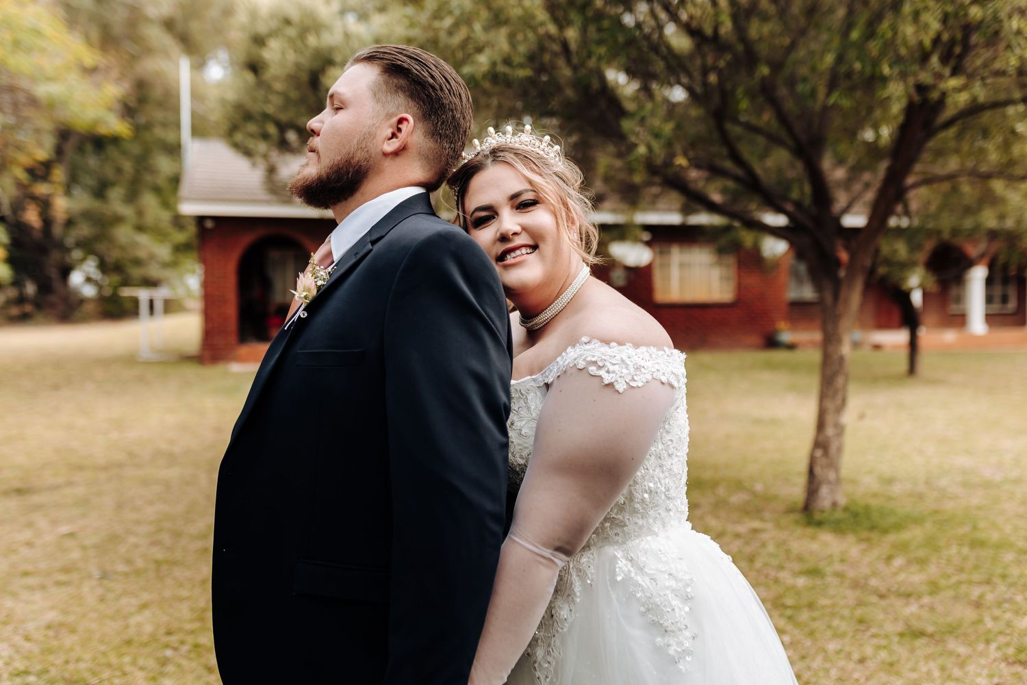 A loving couple embraces outdoors during their rustic autumn wedding while wearing formal attire.