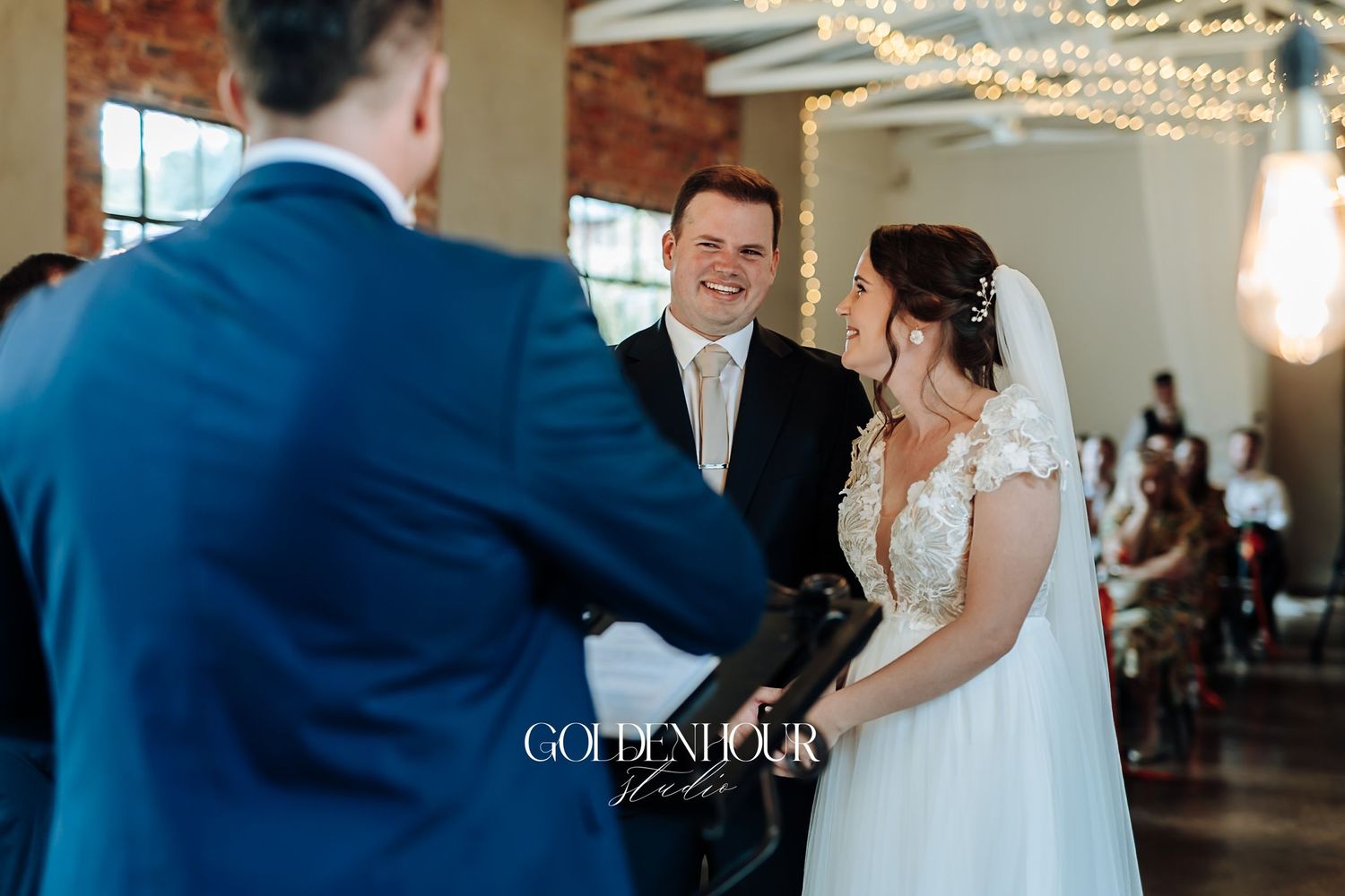 Groom smiling at bride during wedding ceremony in an elegant indoor venue.