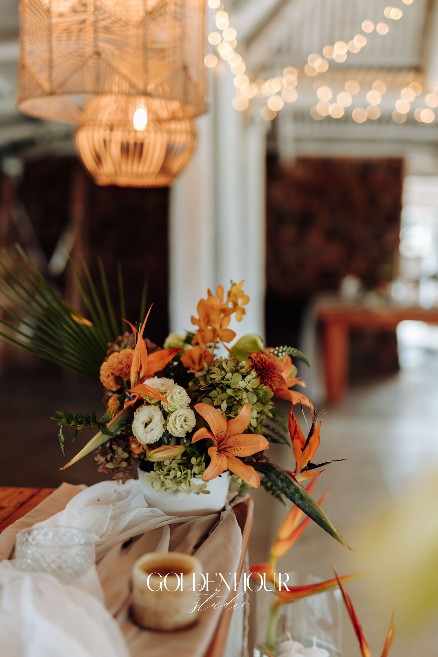 Elegant floral centerpieces with orange lilies and white flowers arranged in glass vases on a formal dining table.