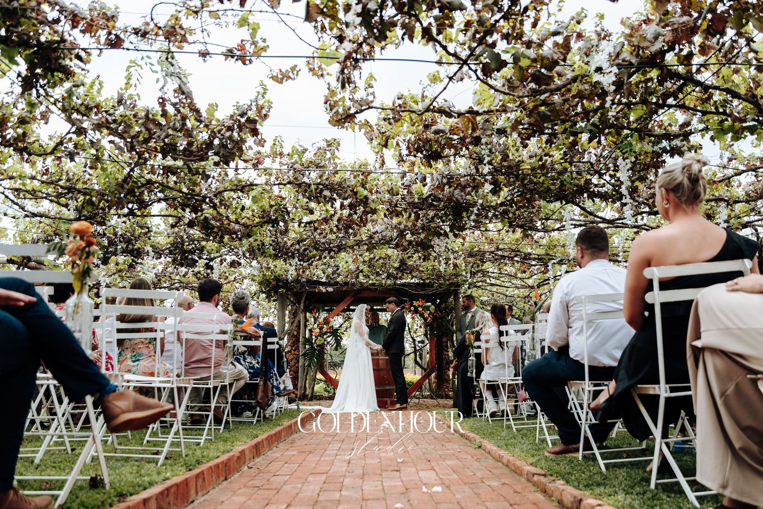 Outdoor wedding ceremony setup with white chairs arranged in rows under blooming trees.