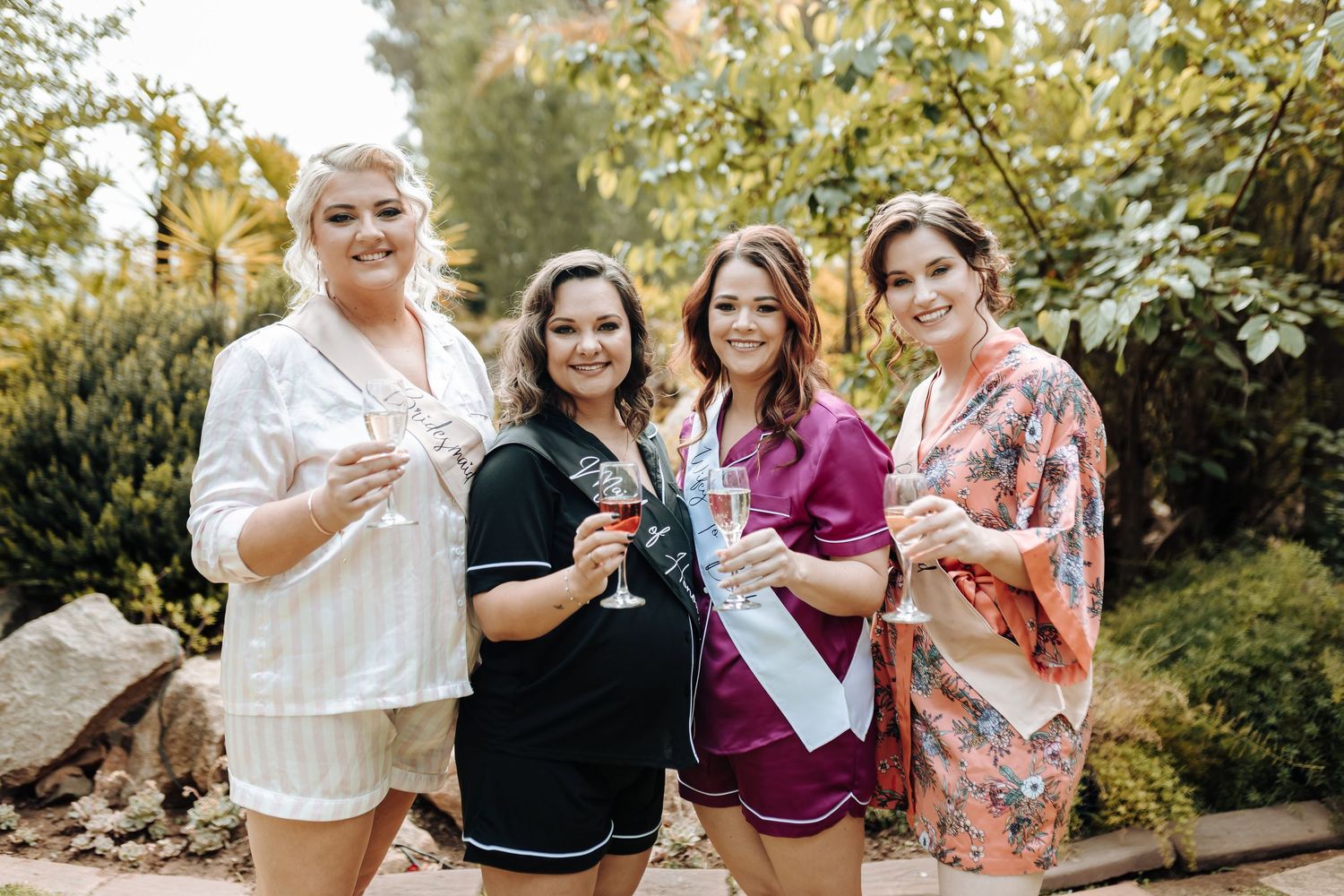 Four friends share drinks and laughter during an outdoor celebration.