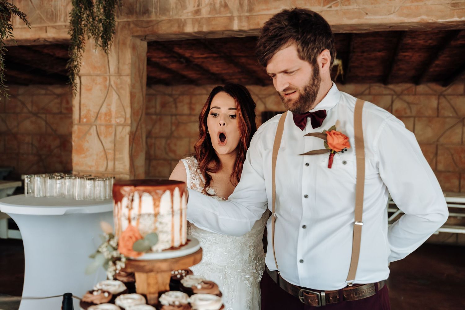 Joyful wedding moment at dessert table with cake and cupcake tower display.