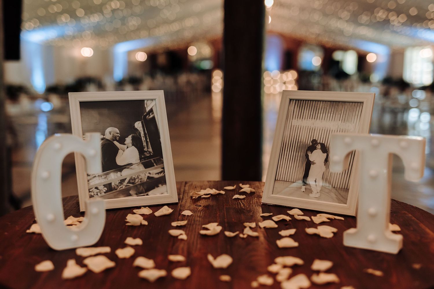 Two vintage photographs displayed with illuminated decorative letters on a dark wooden table.