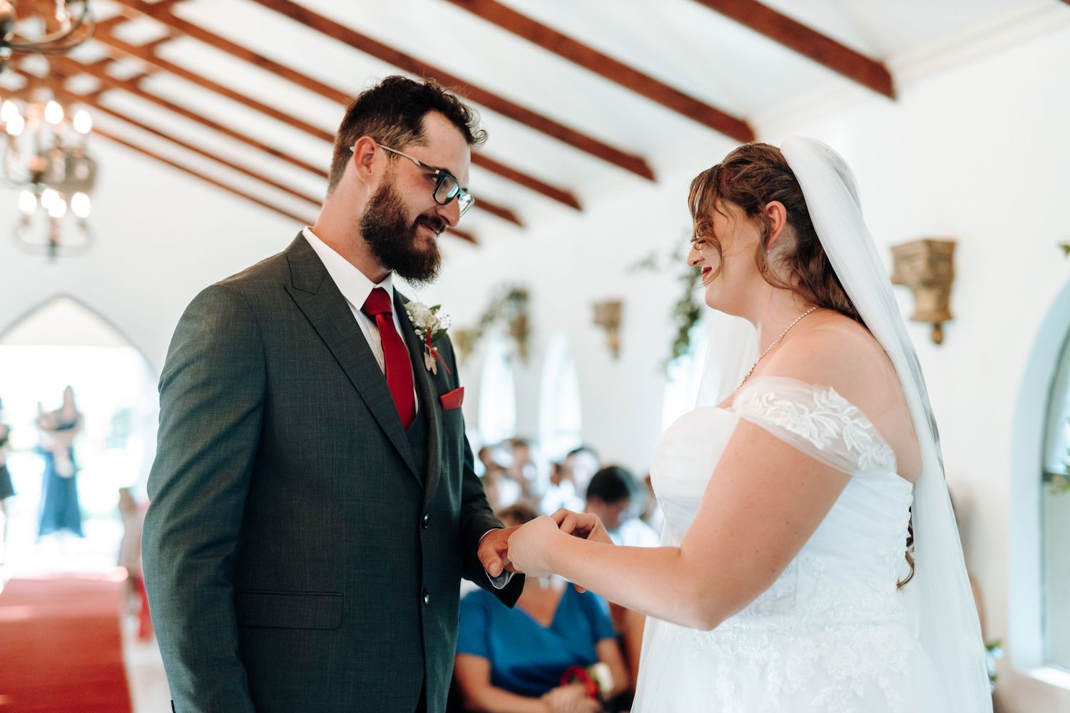 Wedding couple sharing heartfelt vows during their ceremony in a sunlit chapel.