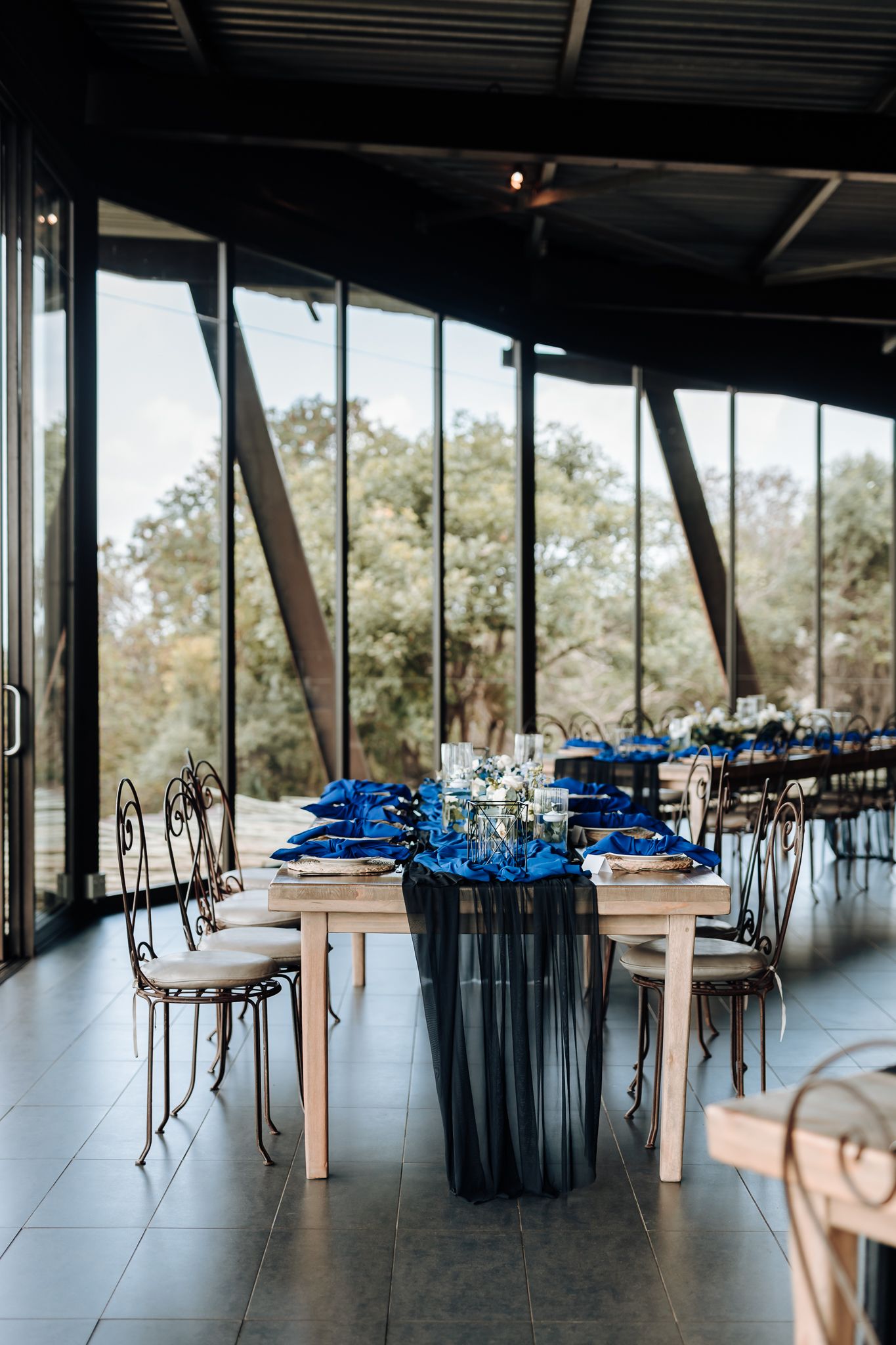 Modern reception venue with floor-to-ceiling windows and blue table settings.