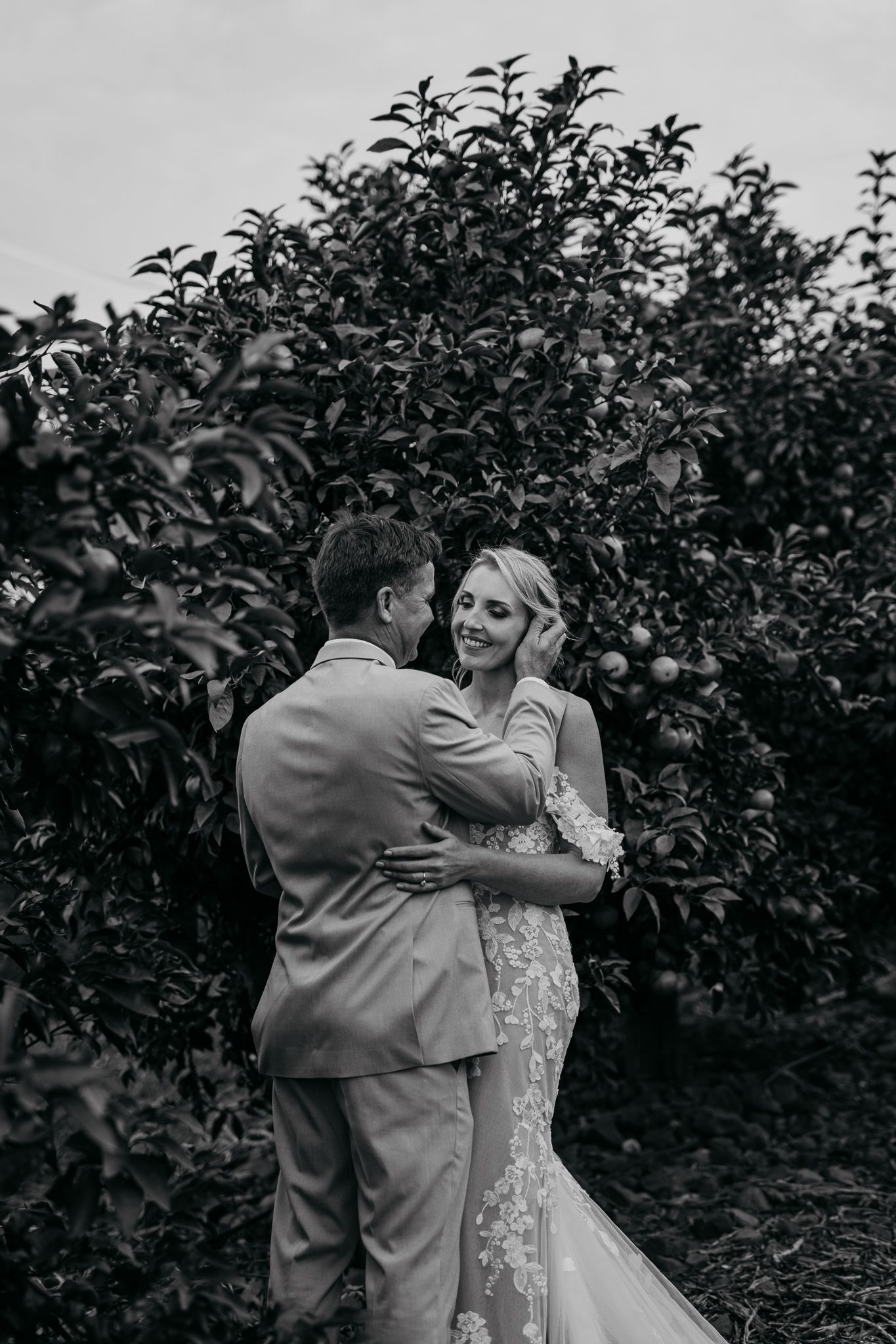 Black and white wedding portrait capturing an intimate moment in an orchard.