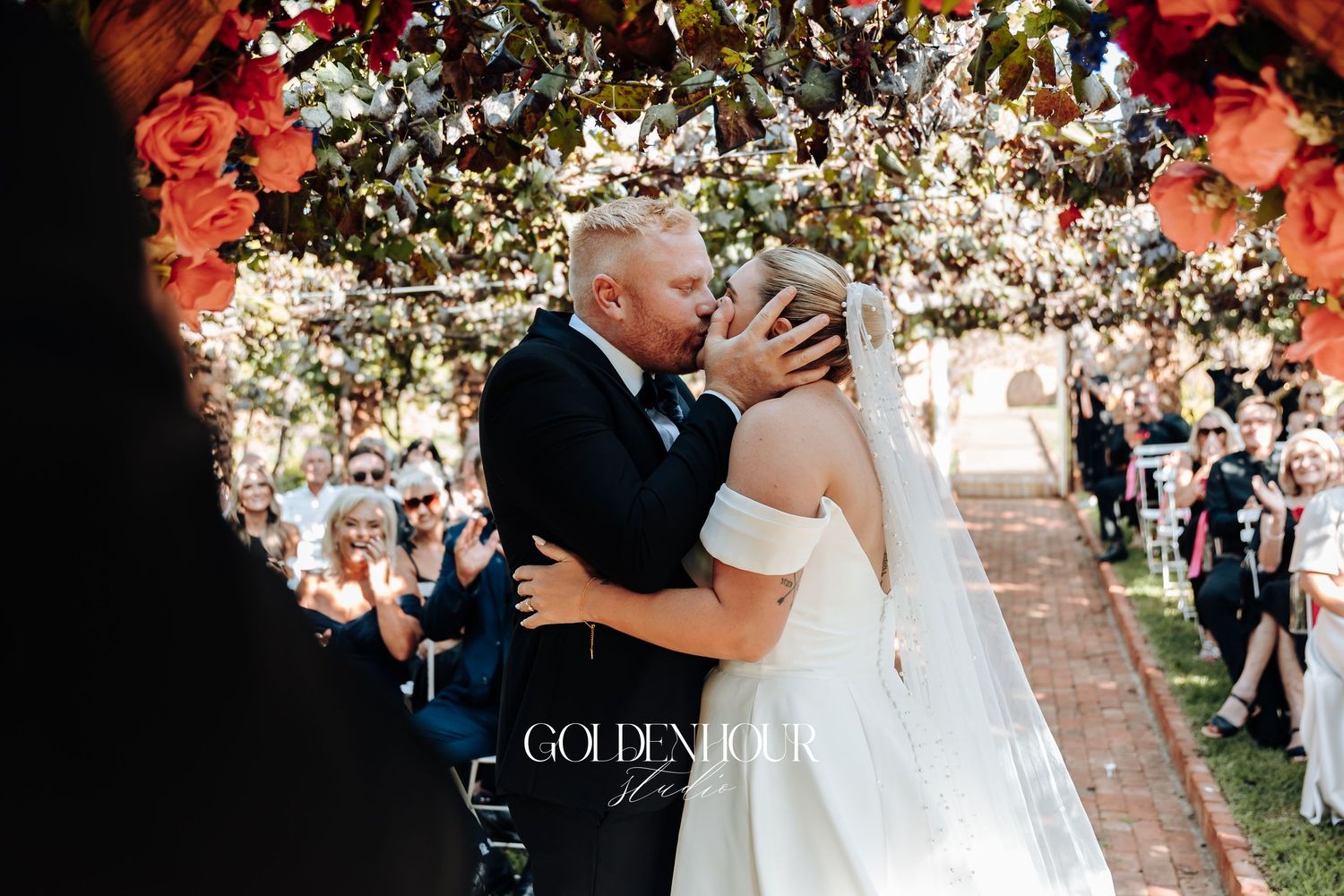 A romantic outdoor garden wedding ceremony with guests seated beneath flowering trees and natural decor.
