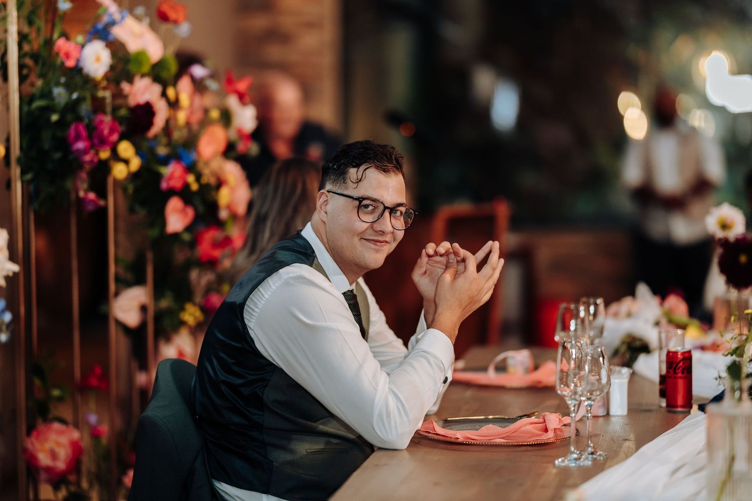 Wedding reception table decorated with vibrant floral arrangements and glowing candles.