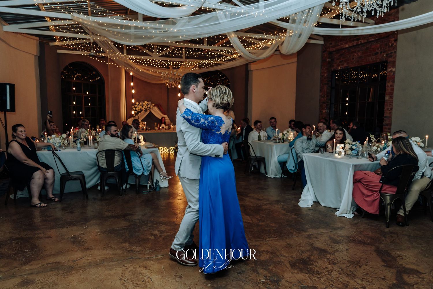 Wedding reception dance floor scene with hanging lights and decorative elements.