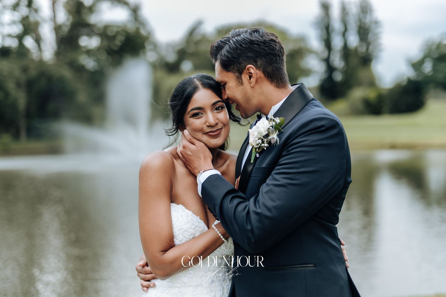 A romantic couple shares an intimate moment by a serene lake during their wedding photoshoot.