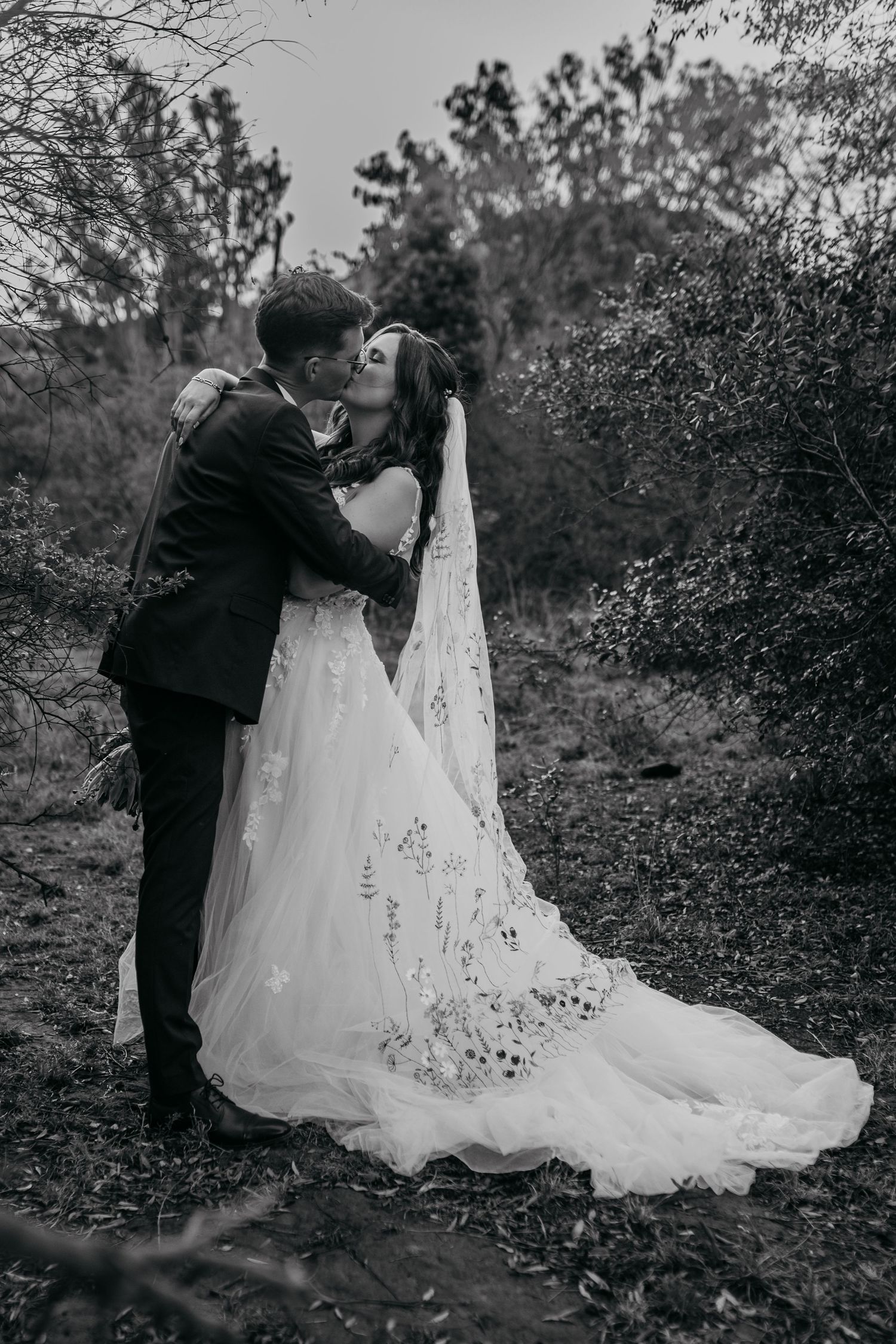 Black and white wedding photo sequence showing a couple in formal attire interacting with a flowing white wedding dress outdoors.