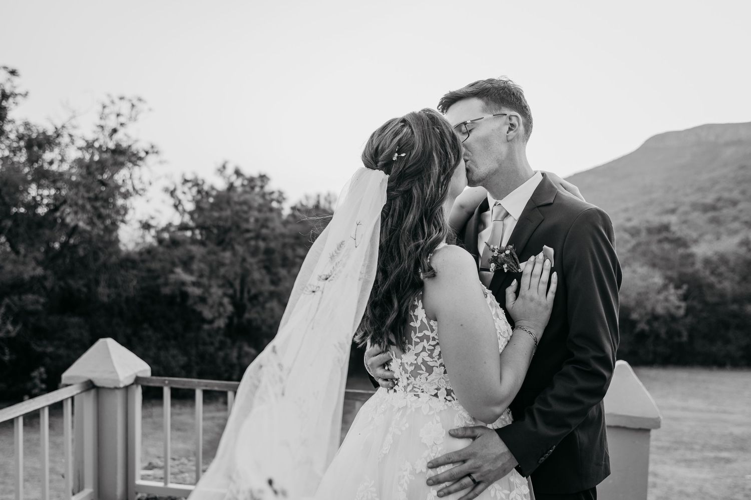 A romantic outdoor wedding photoshoot showing tender moments between a couple in formal attire against a natural backdrop.