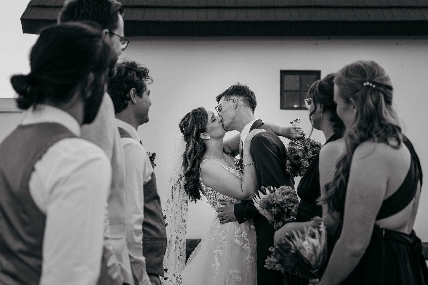 A series of black and white candid photos showing wedding guests dancing and celebrating at a reception.