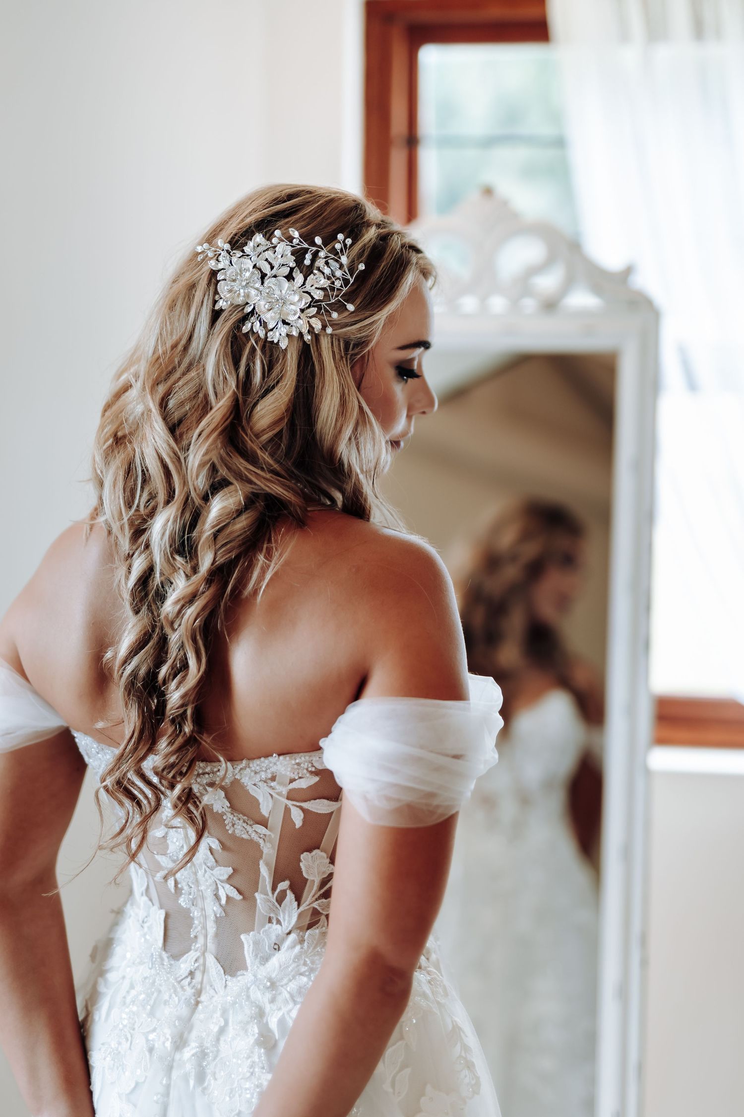 Close-up view of intricate lace details and beading on a white wedding dress with off-shoulder design.