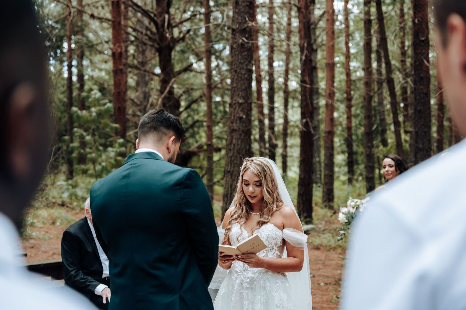 A romantic wedding couple shares an intimate moment together in a sunlit forest setting.