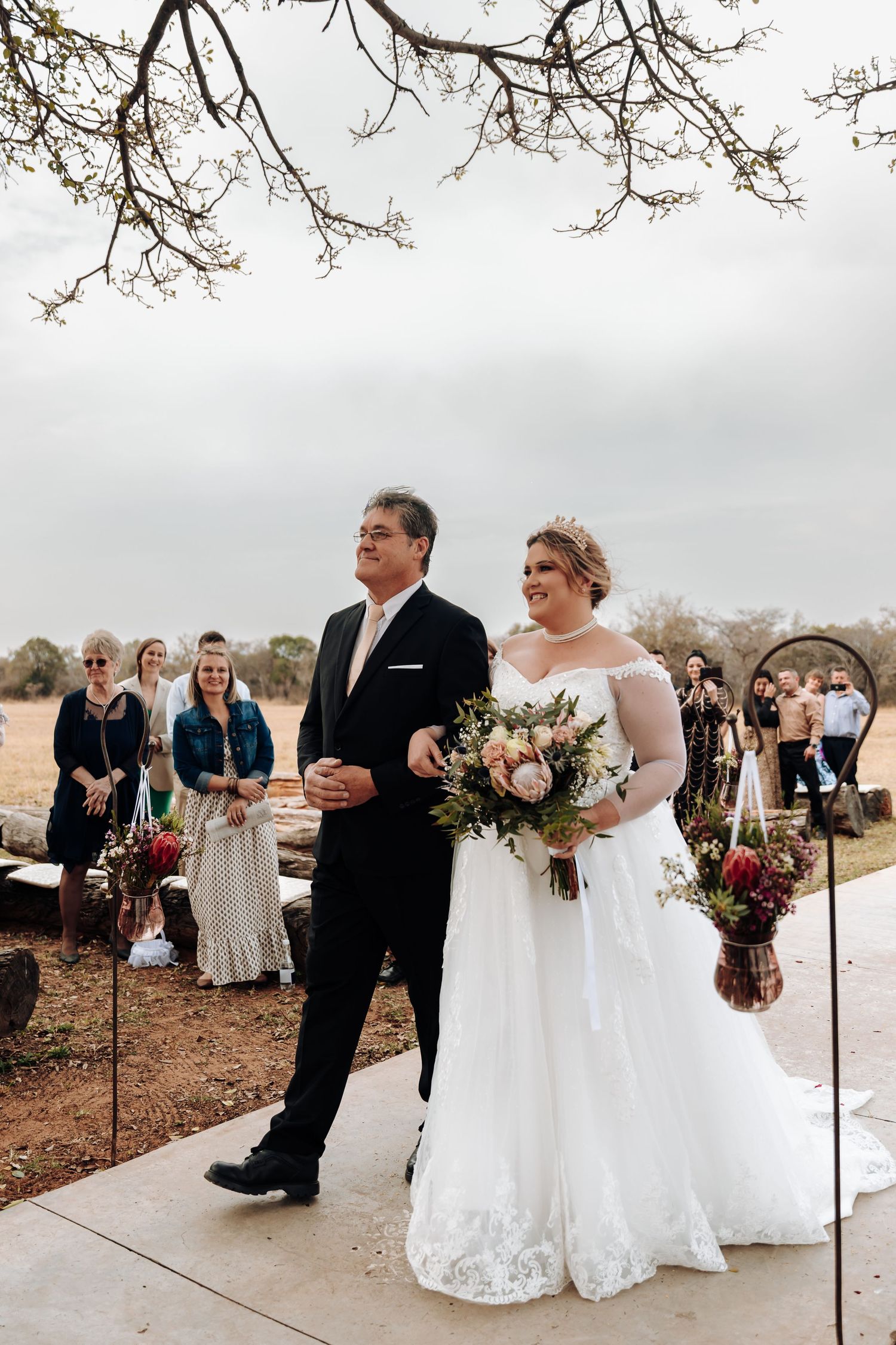 Elegant outdoor winter wedding ceremony with couples standing in row against a cloudy sky background.