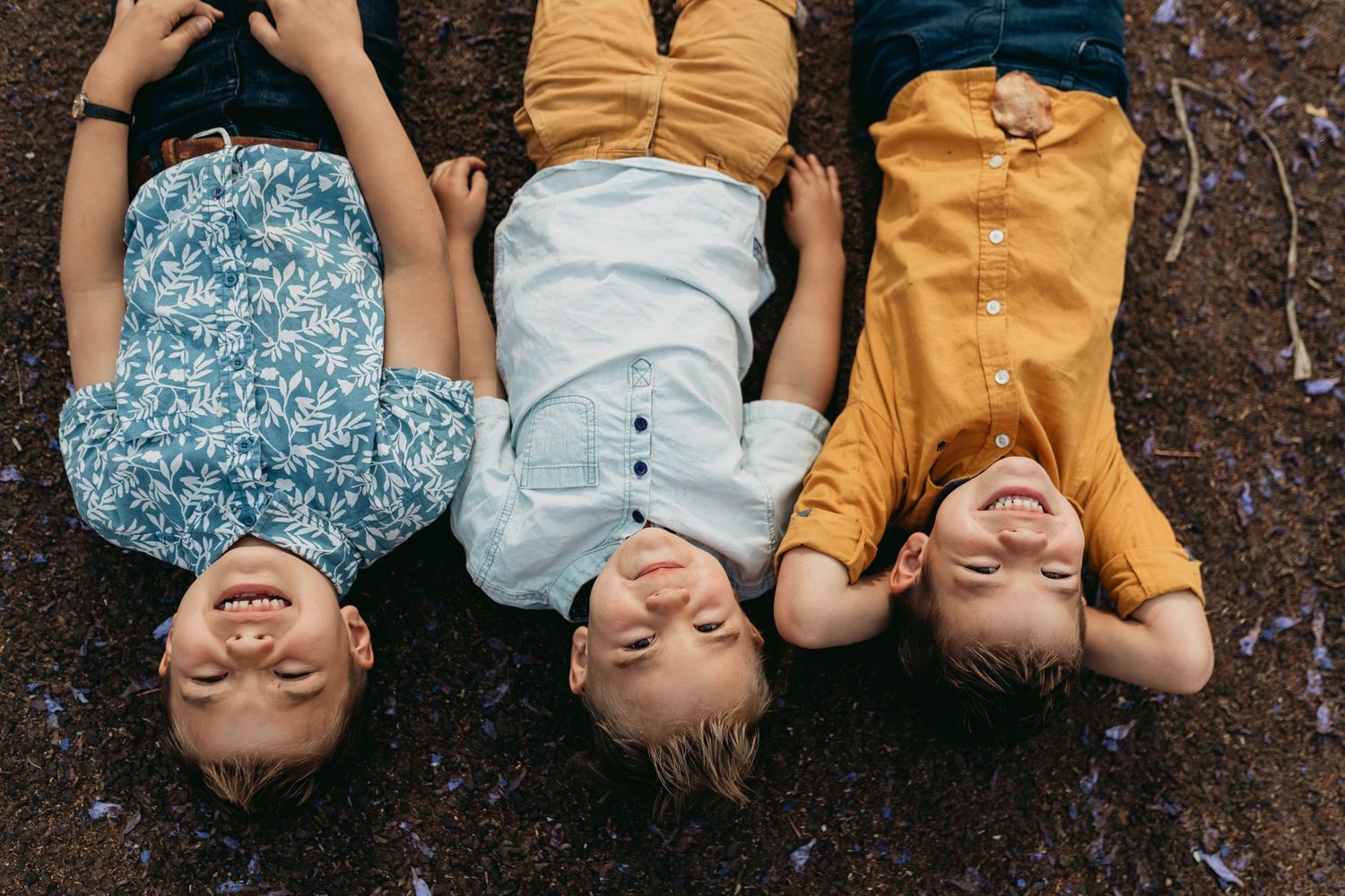 An upside down portrait of a family lying on their backs with big playful smiles on their faces.