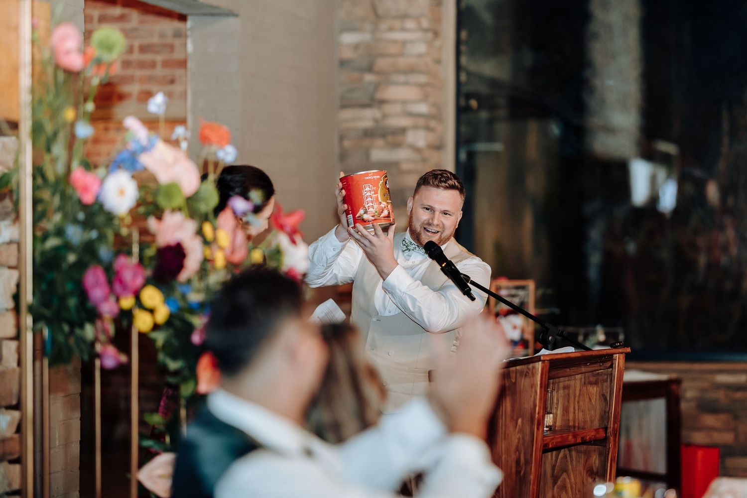 Wedding reception venue decorated with floral arrangements and wooden podium.