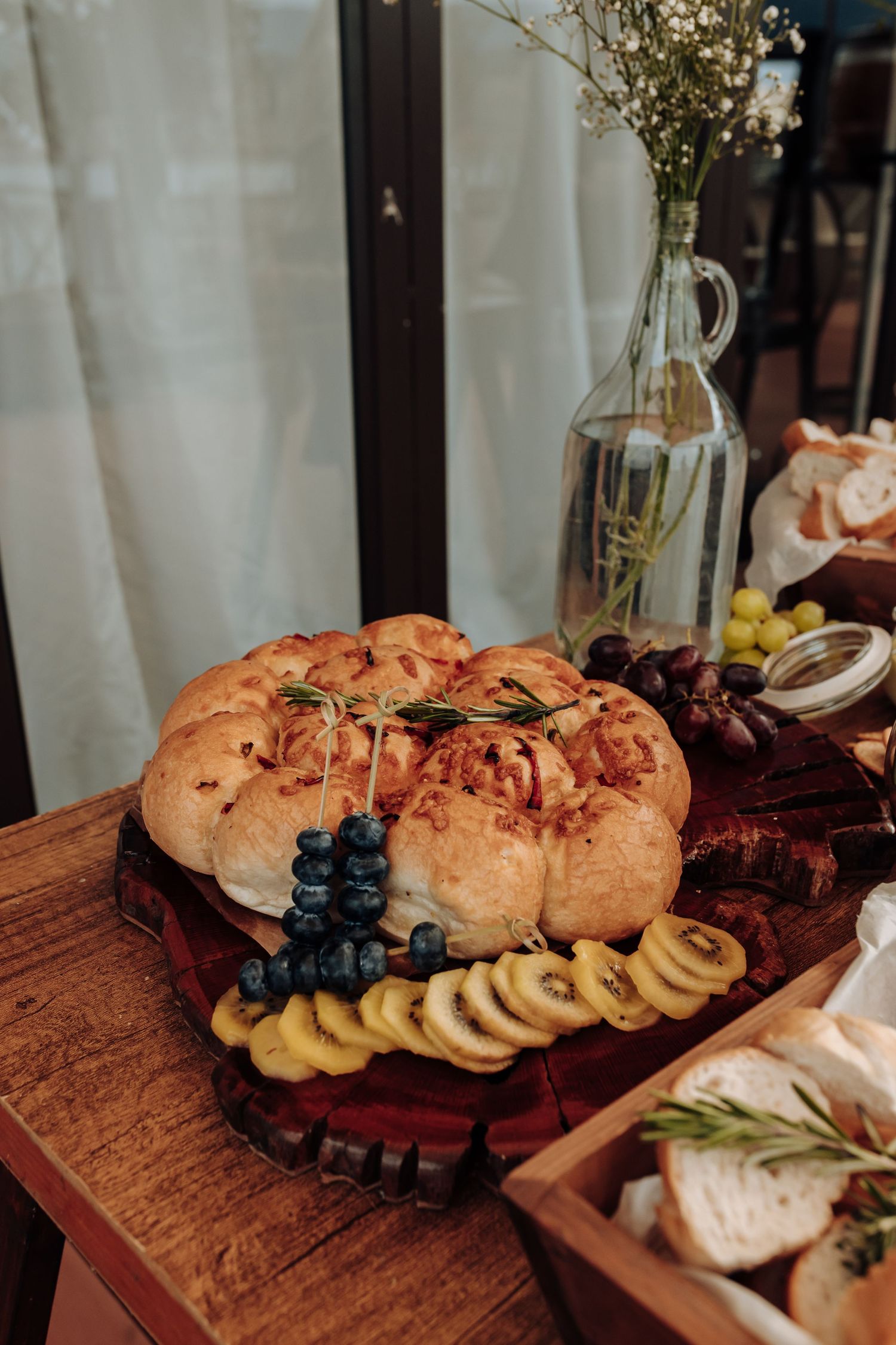Rustic wooden charcuterie board with fresh bread, grapes, and assorted appetizers arranged in an elegant spread.
