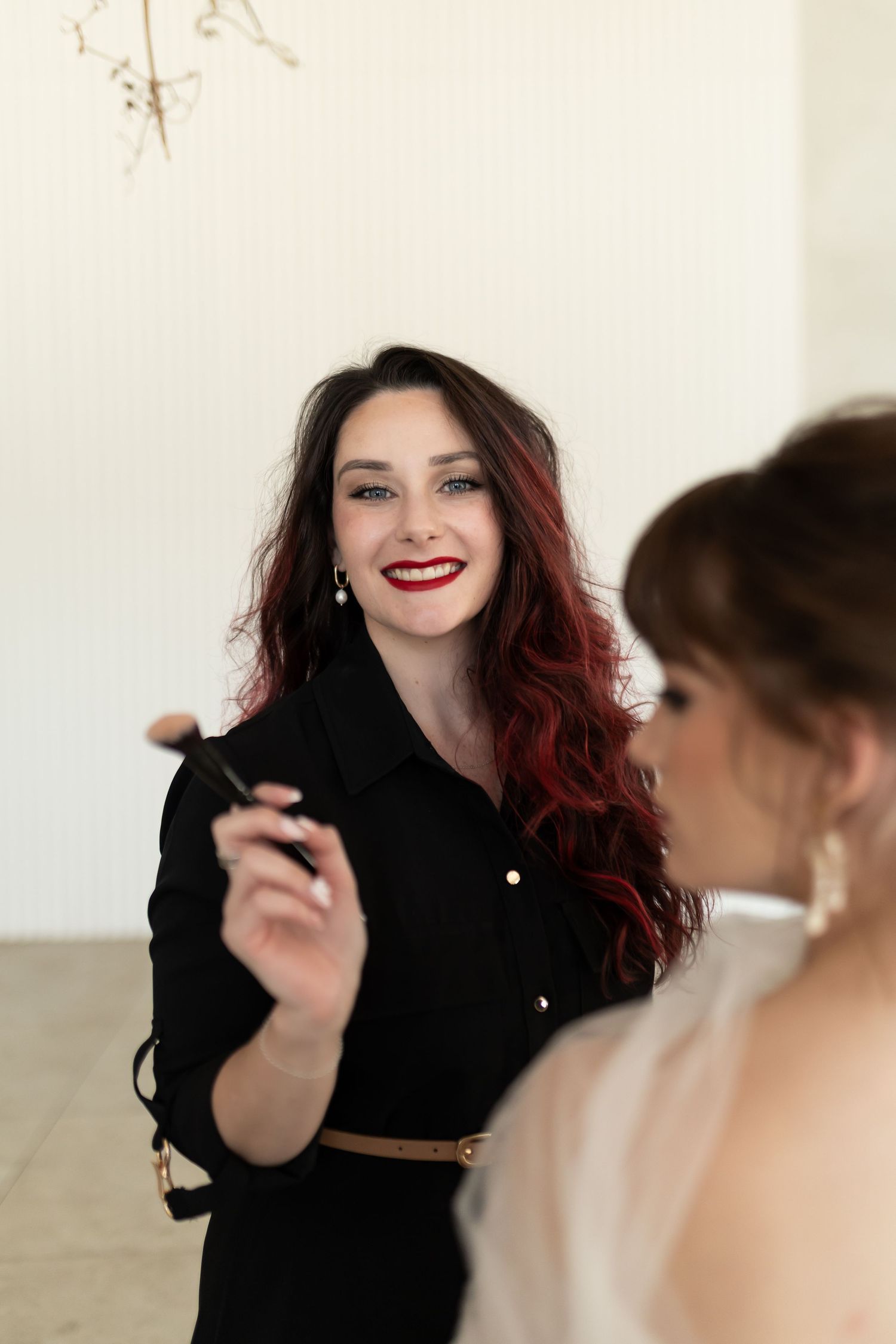 A person with long burgundy hair wearing a black top laughs and gestures expressively in a series of candid shots.