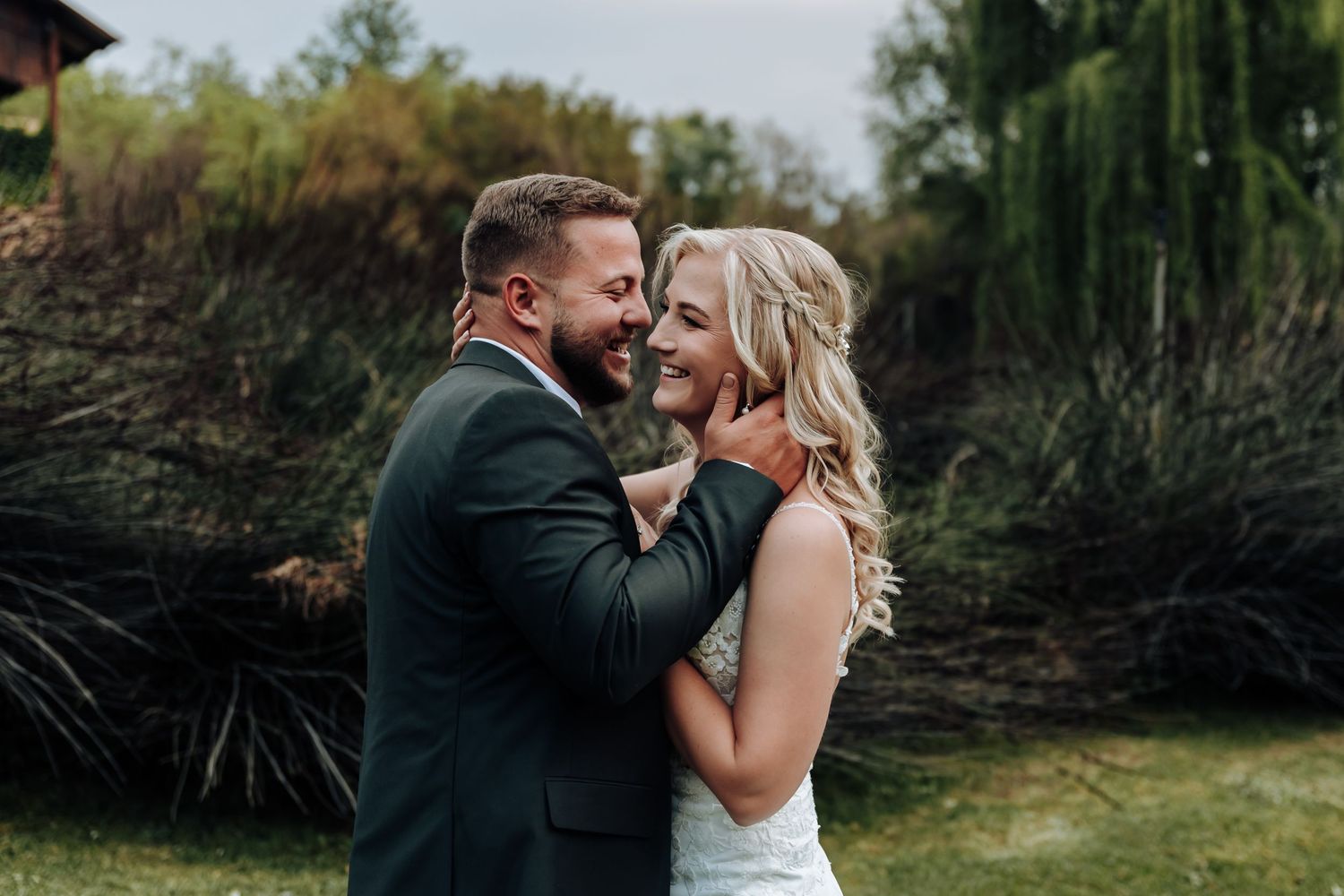 A romantic outdoor wedding moment captured in a garden setting with lush greenery in the background.