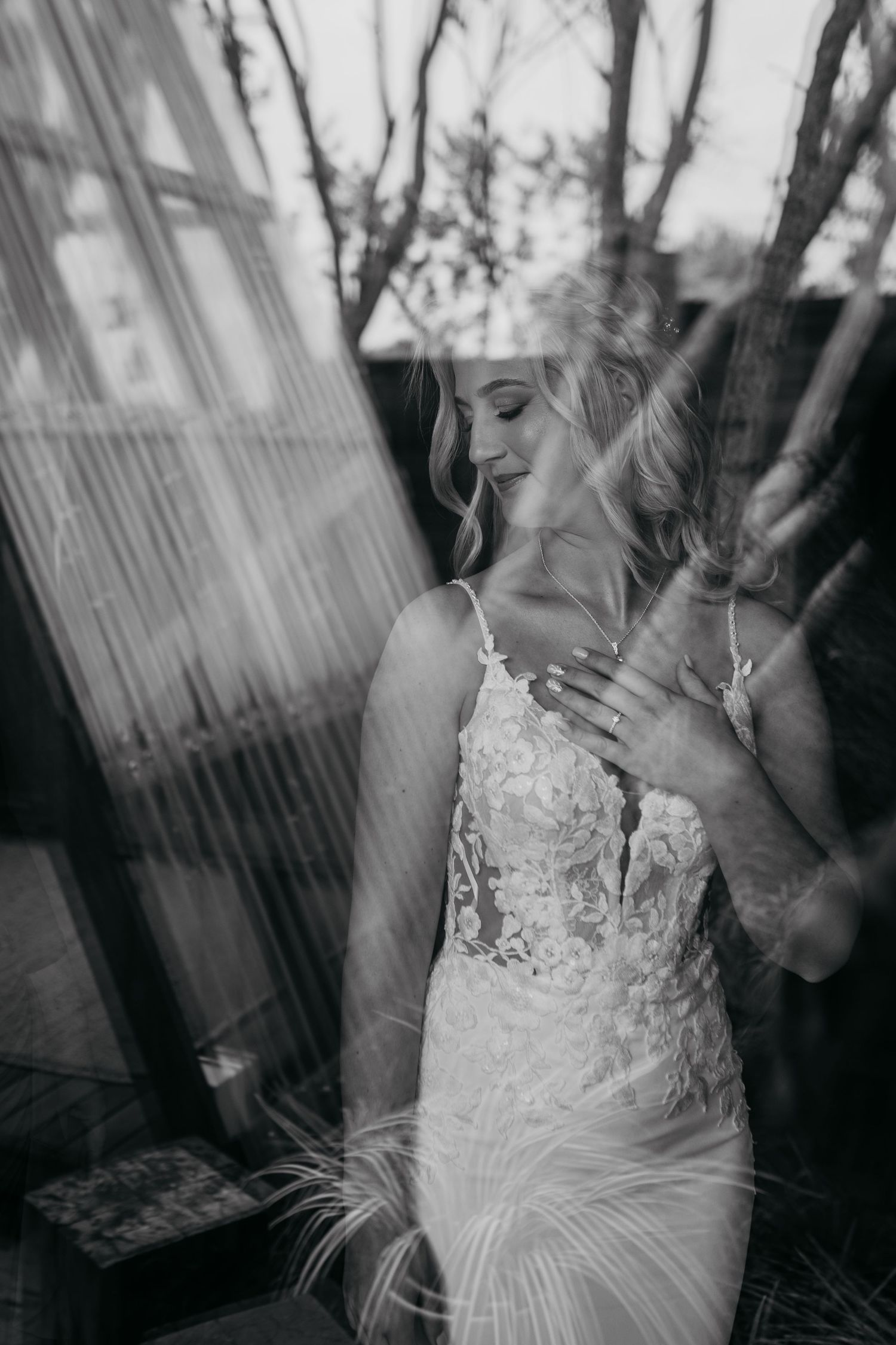 A black and white photo series showing close-up details of a delicate lace and feather wedding dress.