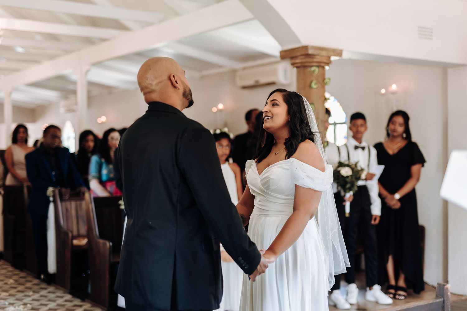A wedding celebration in a bright interior with guests watching the ceremony.