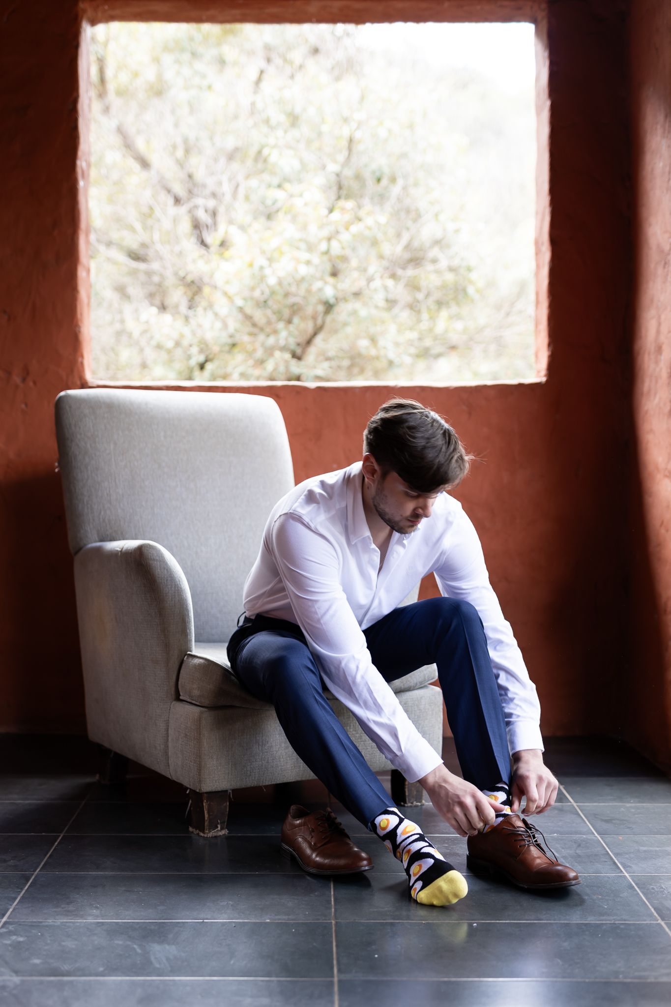 Classic formal attire preparation scene near window with chair.
