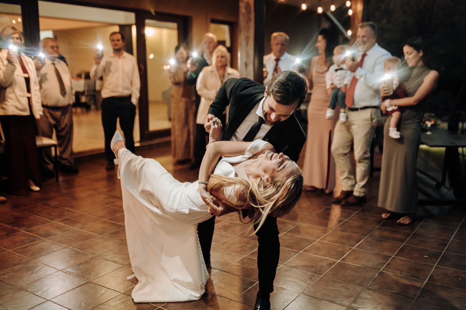 Couple performs a dramatic dip dance move during their wedding celebration.