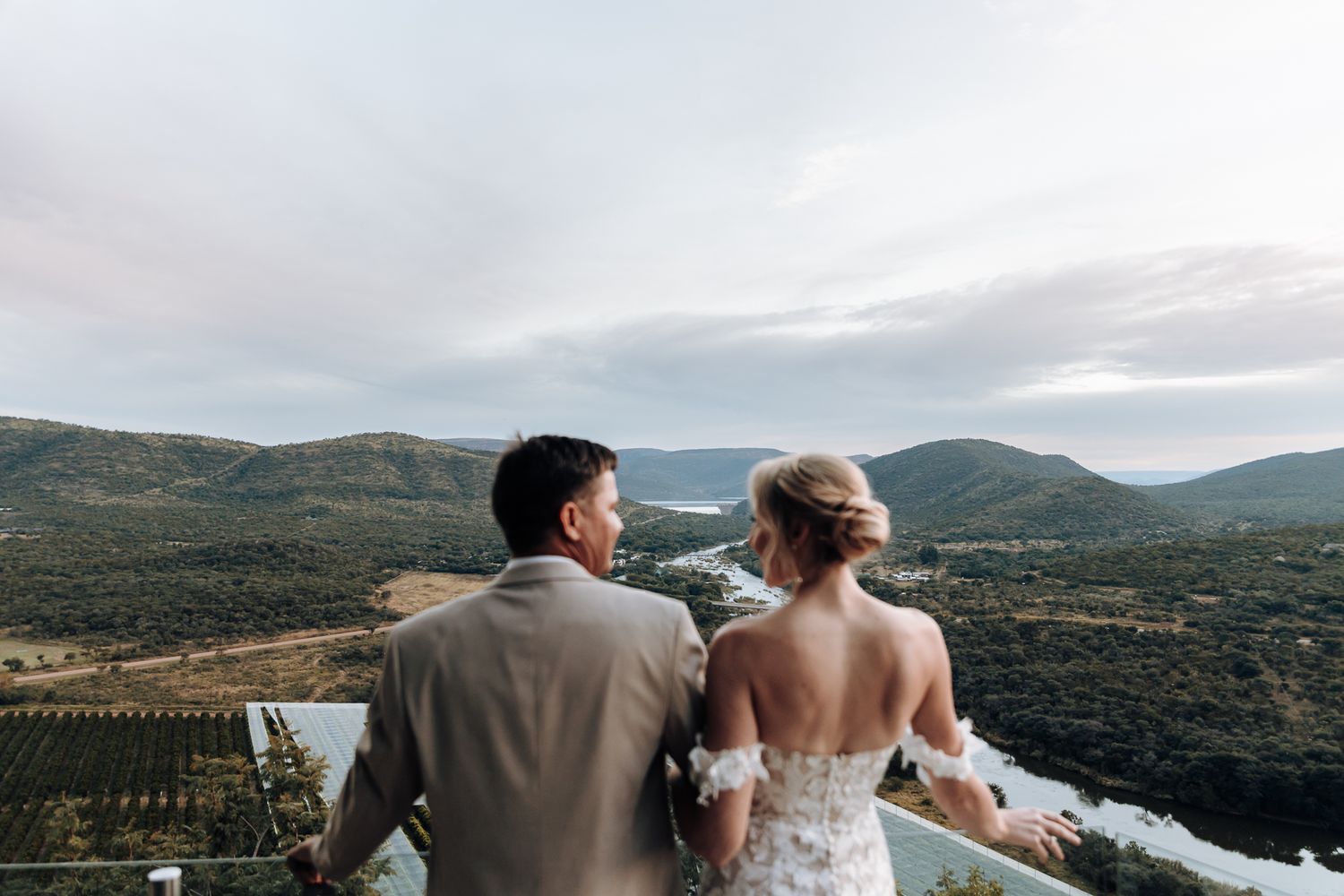 Newlyweds admire the scenic mountain view from their wedding venue overlook.
