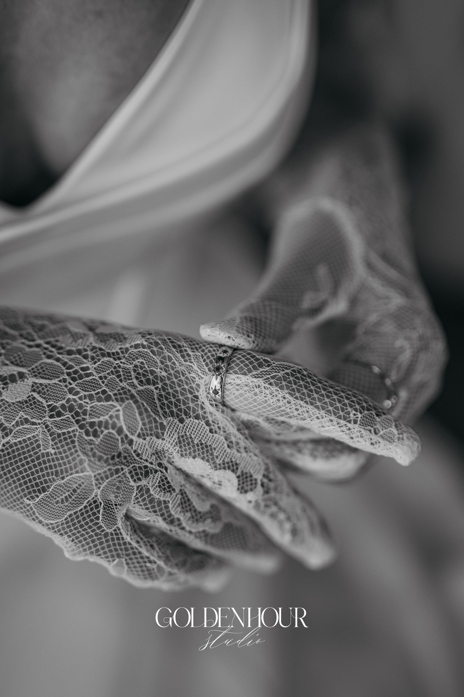 Delicate white lace detail from a wedding dress shown in black and white close-up photography.