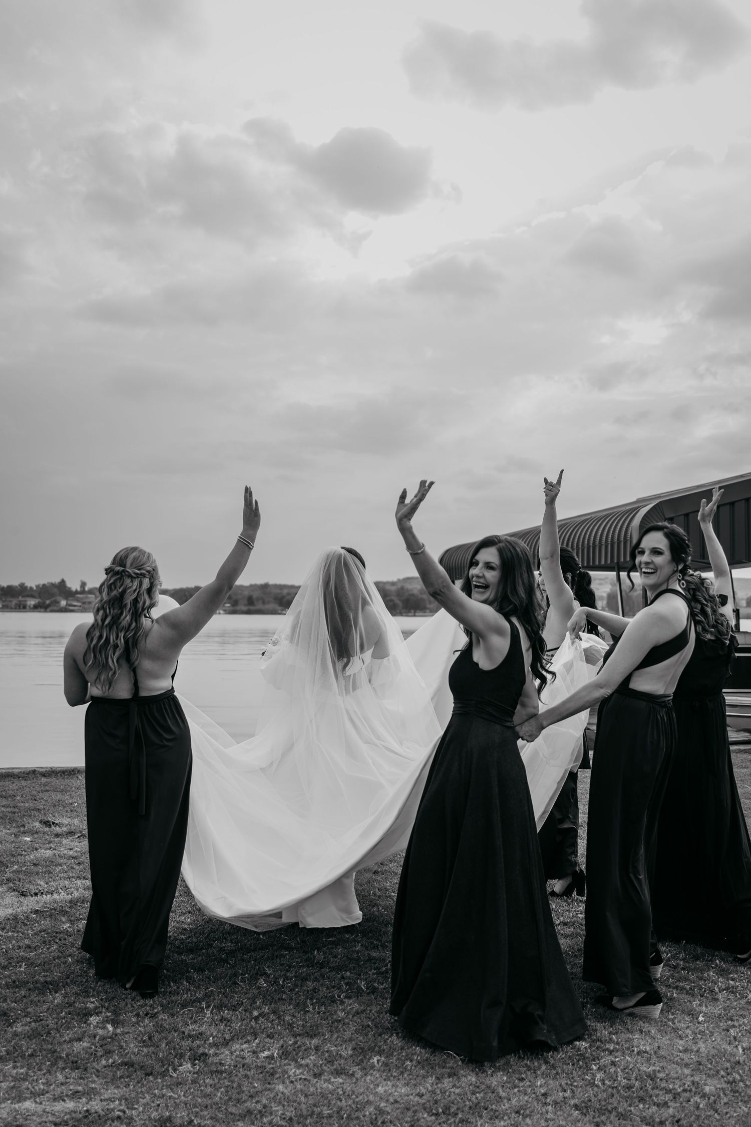 A group in black dresses stands in a field holding white fabric that billows in the wind creating a dramatic scene.