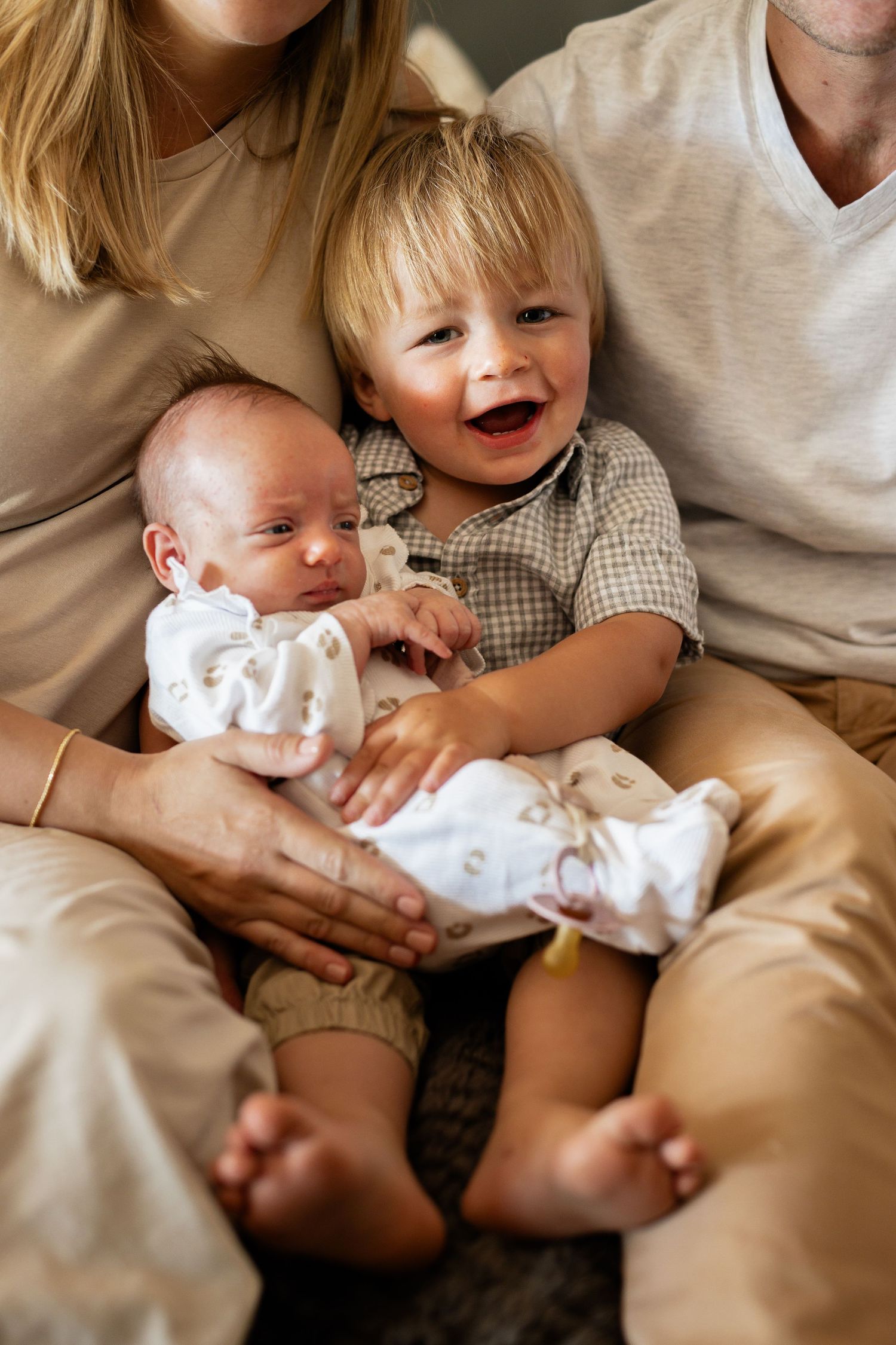 Sweet candid moments of family snuggling together on white bedding showing tender interactions.