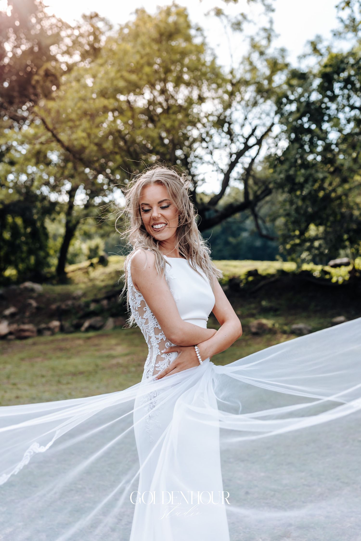 A flowing white wedding dress with lace details captured in natural sunlight.