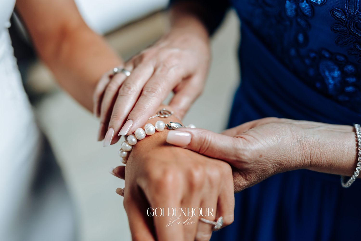 Two hands with wedding rings intertwined in an intimate moment against a navy blue background.