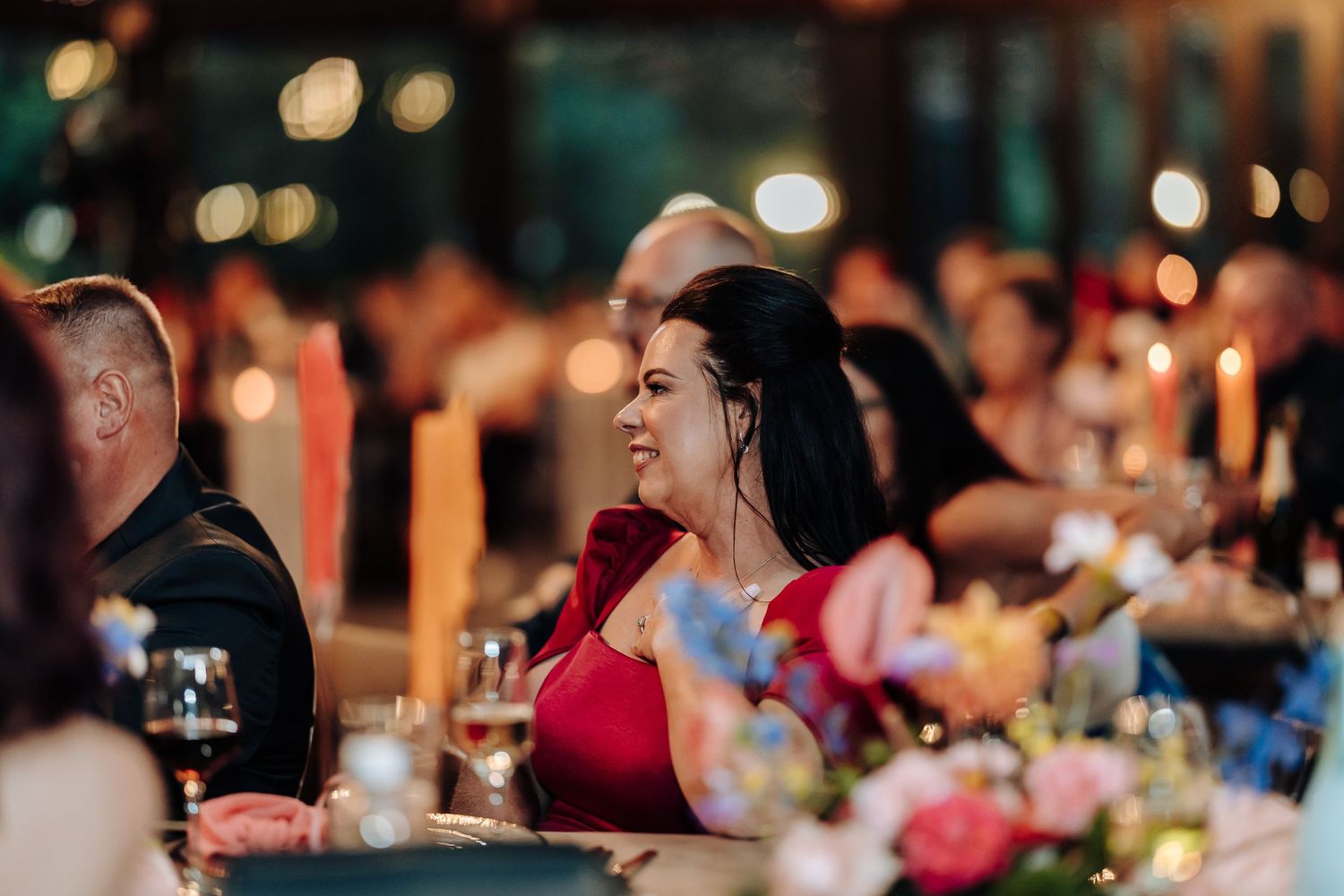 Guests seated at an elegant evening wedding reception with candlelit tables and ambient lighting.