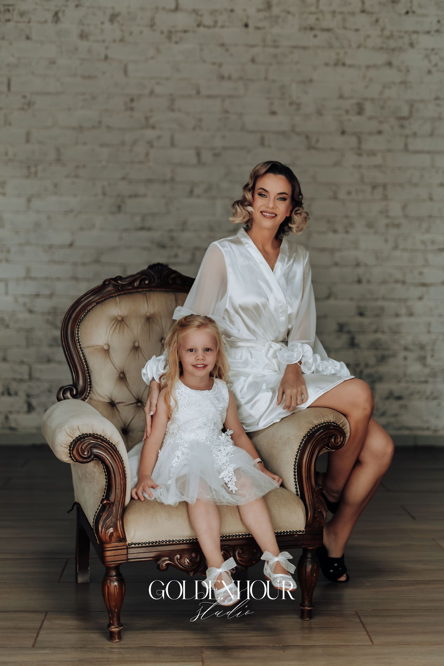 Matching white silk robes worn during intimate family portrait session on vintage sofa.