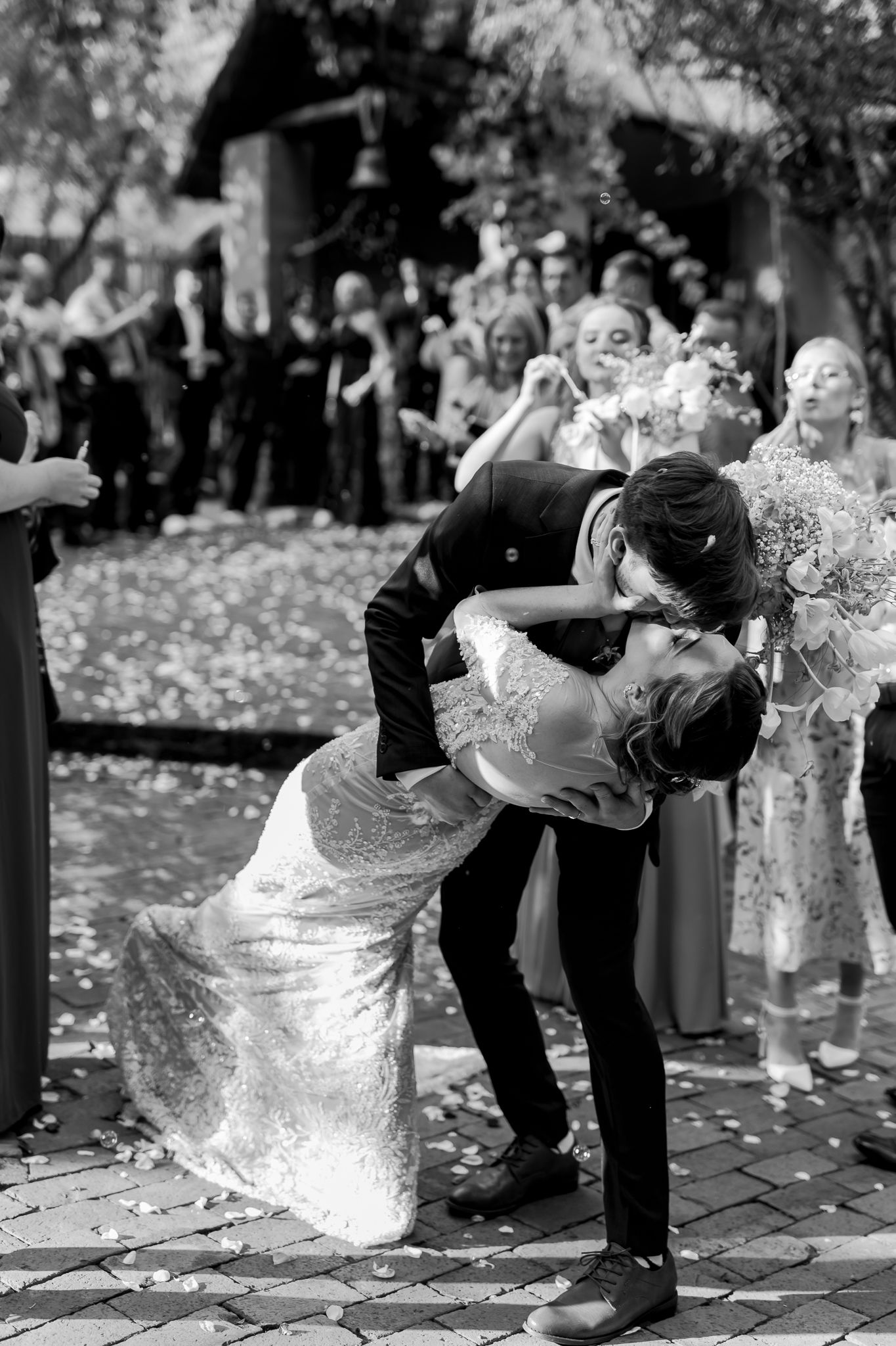 A dramatic black and white dip pose captured during a wedding celebration with fallen leaves on the ground.