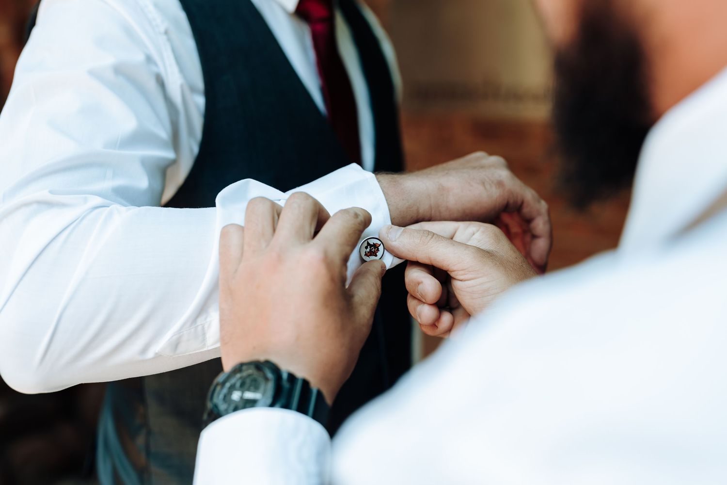 Close-up of hands adjusting cufflinks on white dress shirt sleeve.