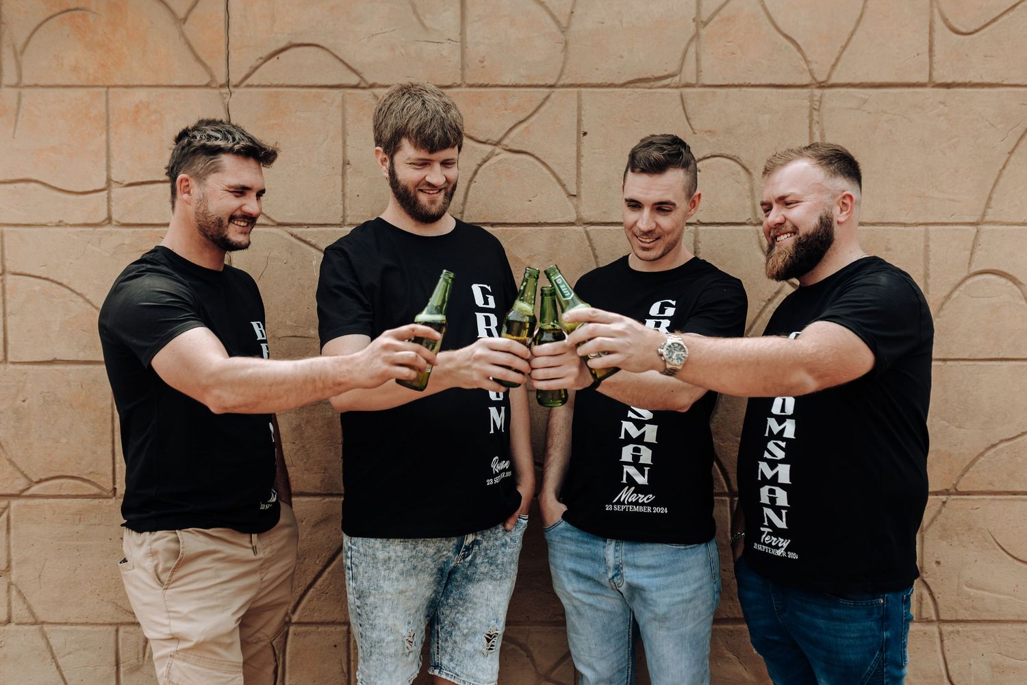 Friends clinking bottles together in celebratory toast while wearing matching shirts.