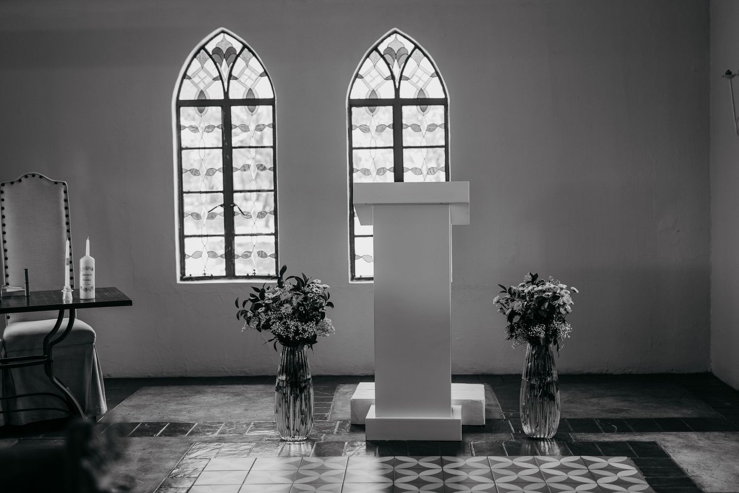 Black and white photo of church interior with gothic windows and ceremonial podium.
